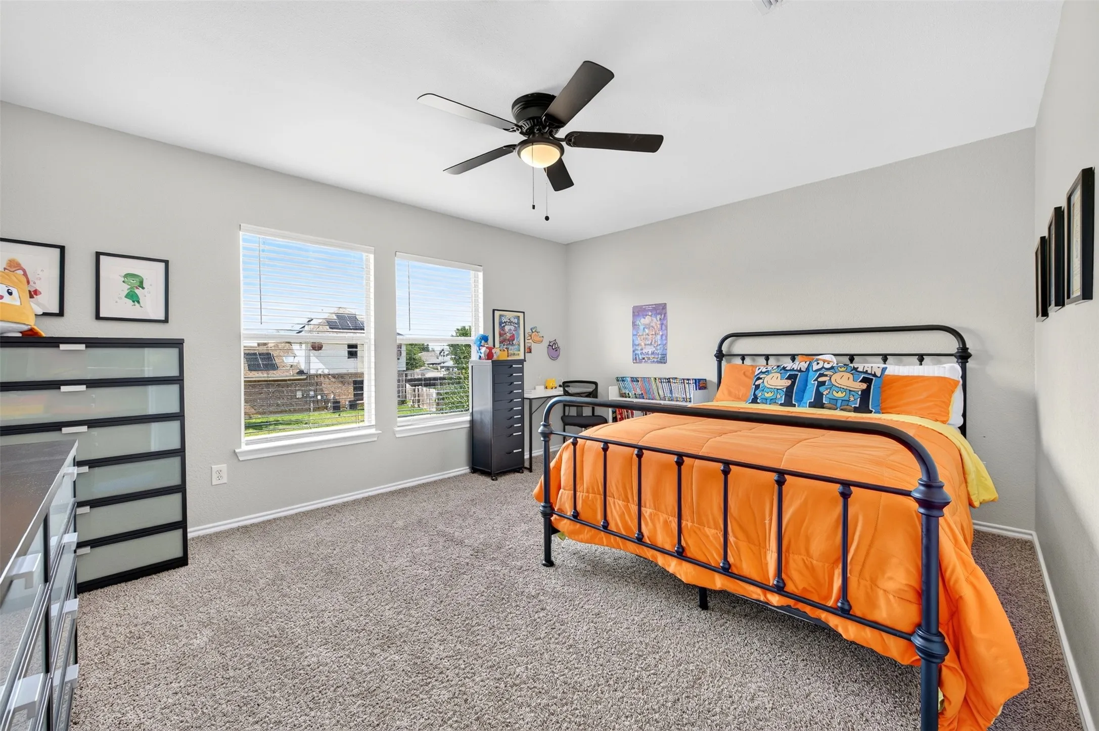 Carpeted room featuring two prominent windows with blinds, a ceiling fan with integrated lighting, and light gray wall finishes