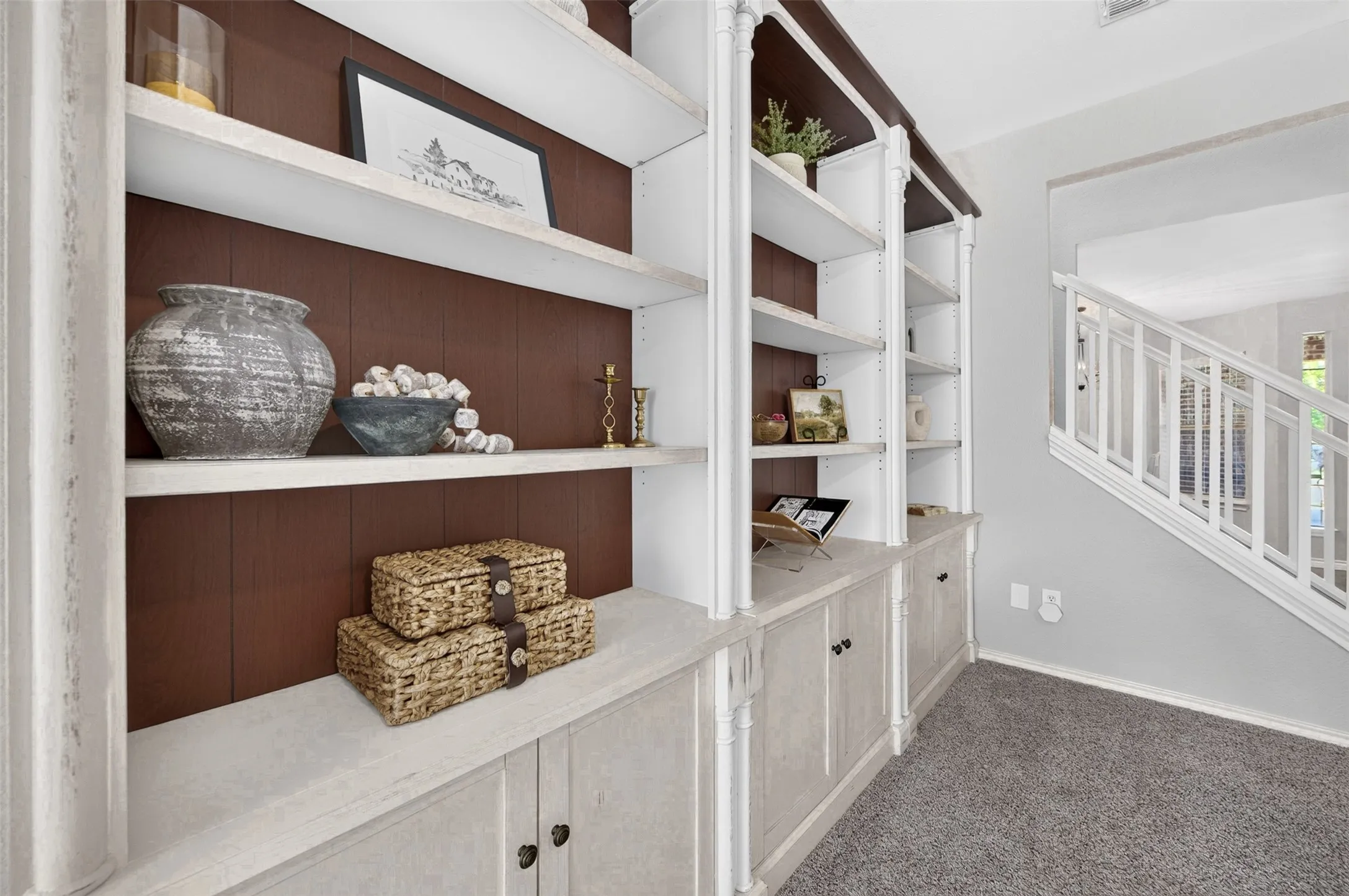 Built-in shelving unit featuring white finishes and a rich wood-toned backing