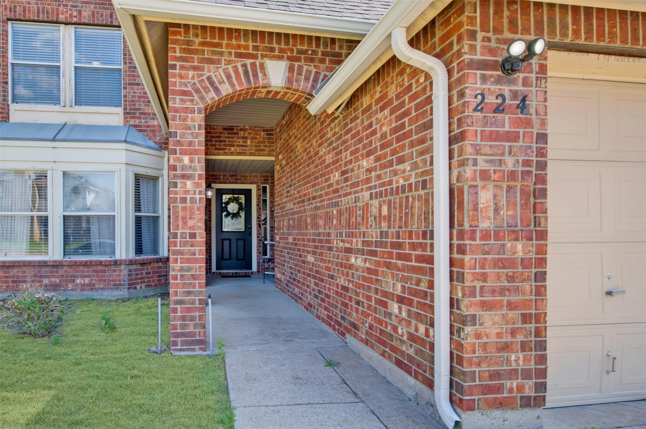 Brick facade with an arched entry, a bay window, and an attached garage