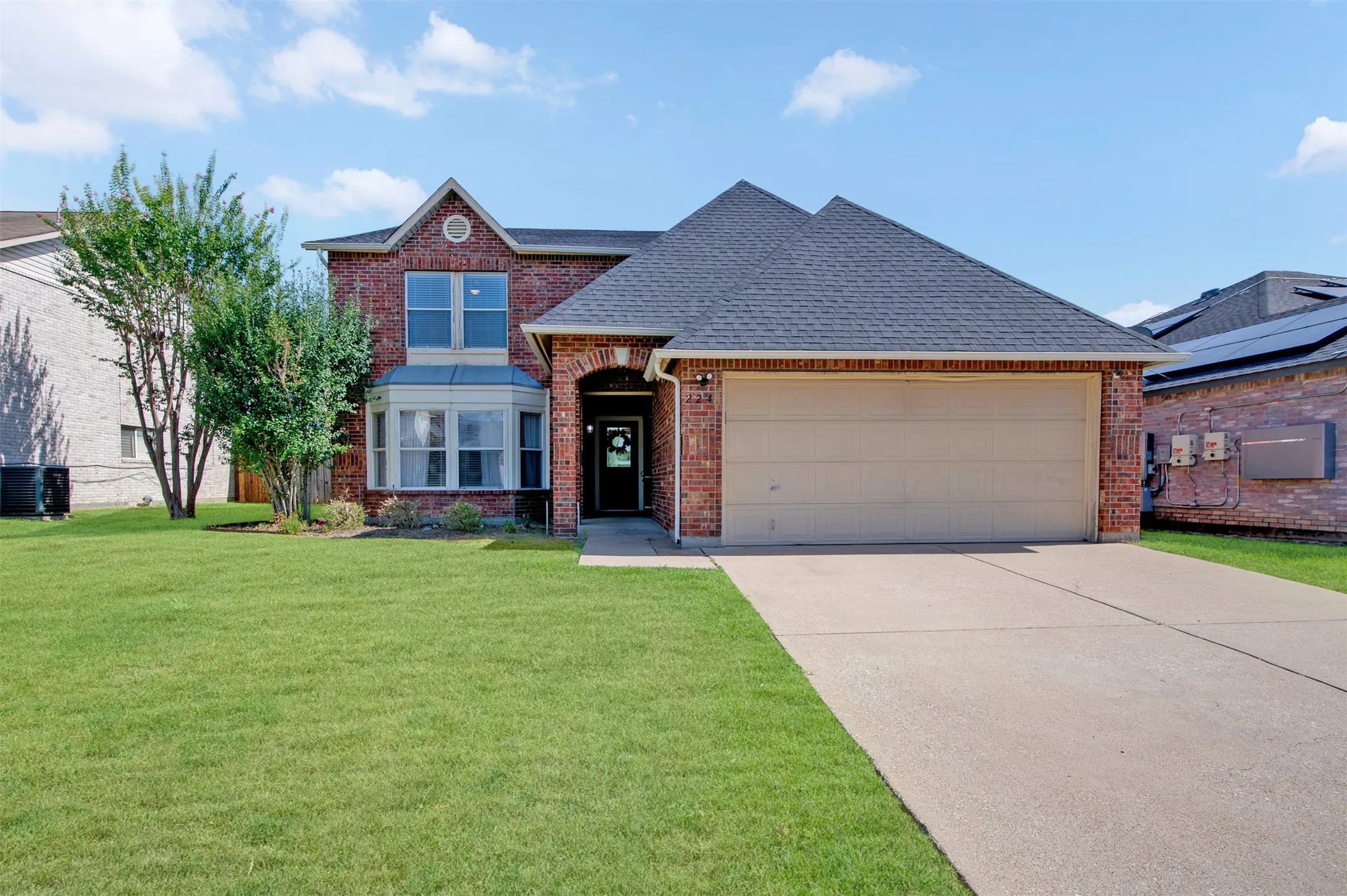 Red brick exterior with a dark shingle roof and a bay window