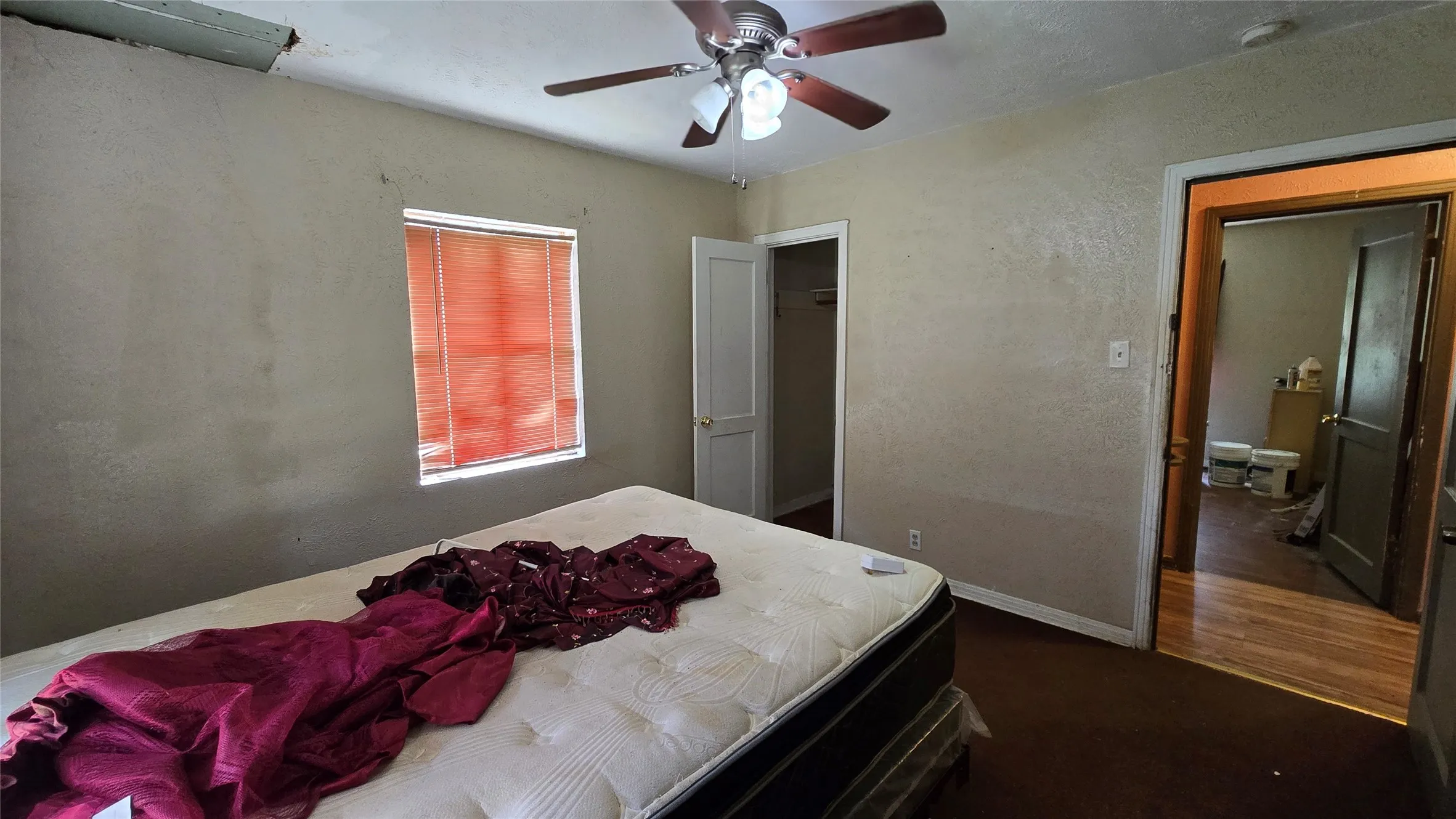 Bedroom featuring a ceiling fan with light fixture, window with blinds, and brown carpeting