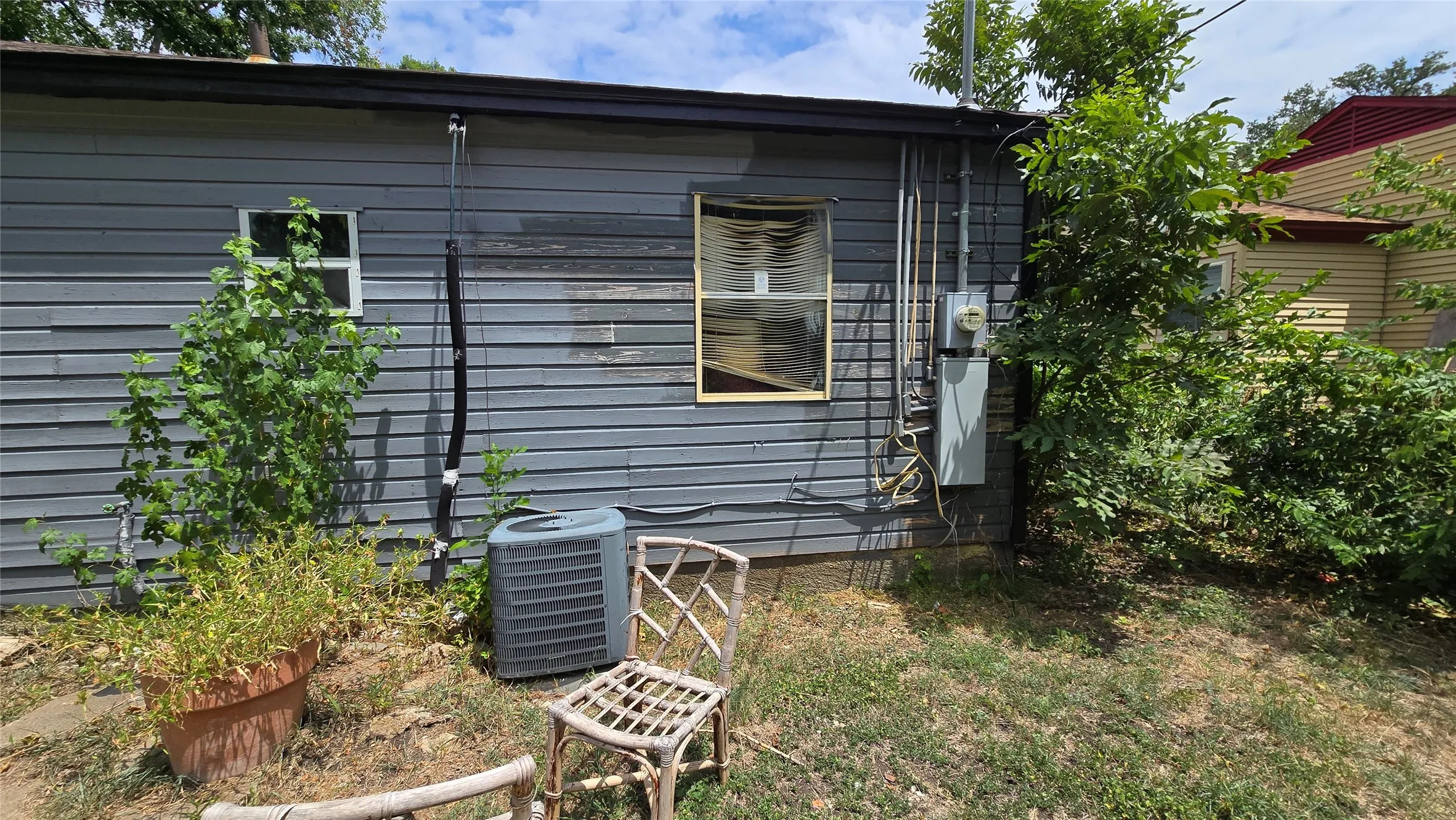 Side exterior with gray horizontal siding, two windows, and an outdoor HVAC unit