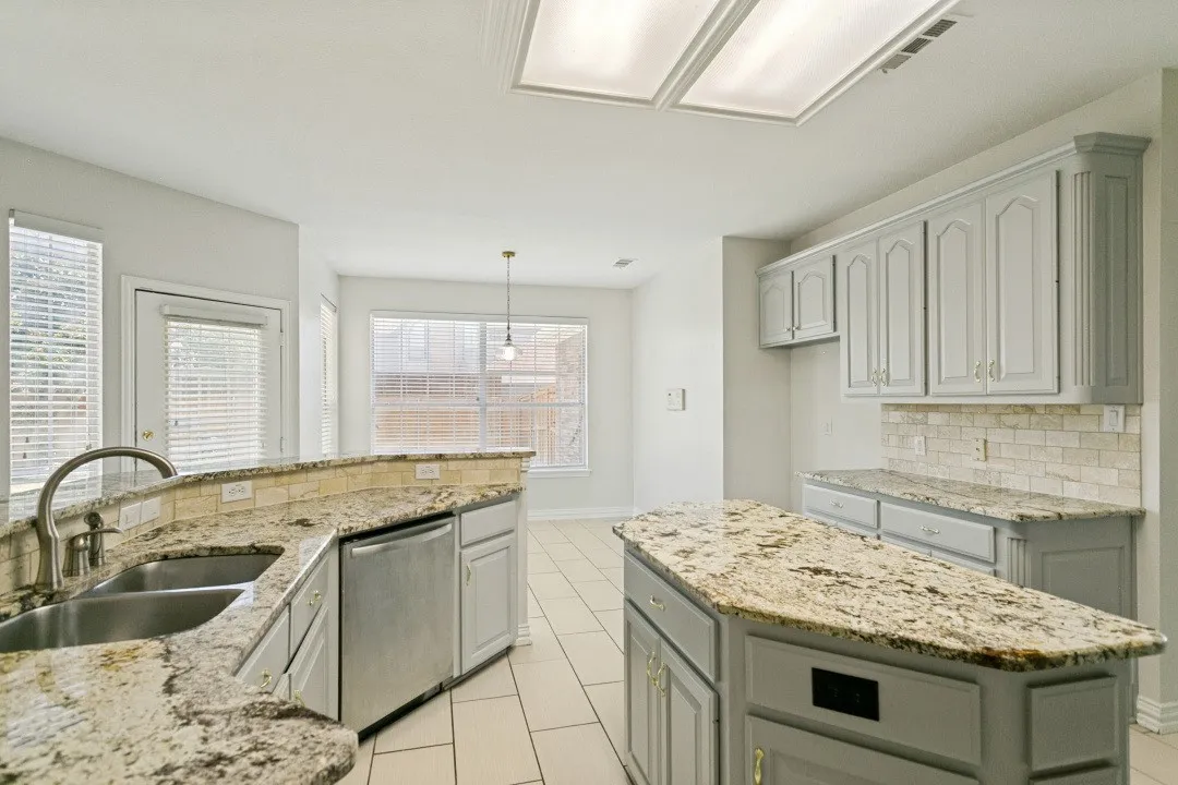 Kitchen featuring light-toned cabinetry, granite countertops, tile flooring, and a subway tile backsplash