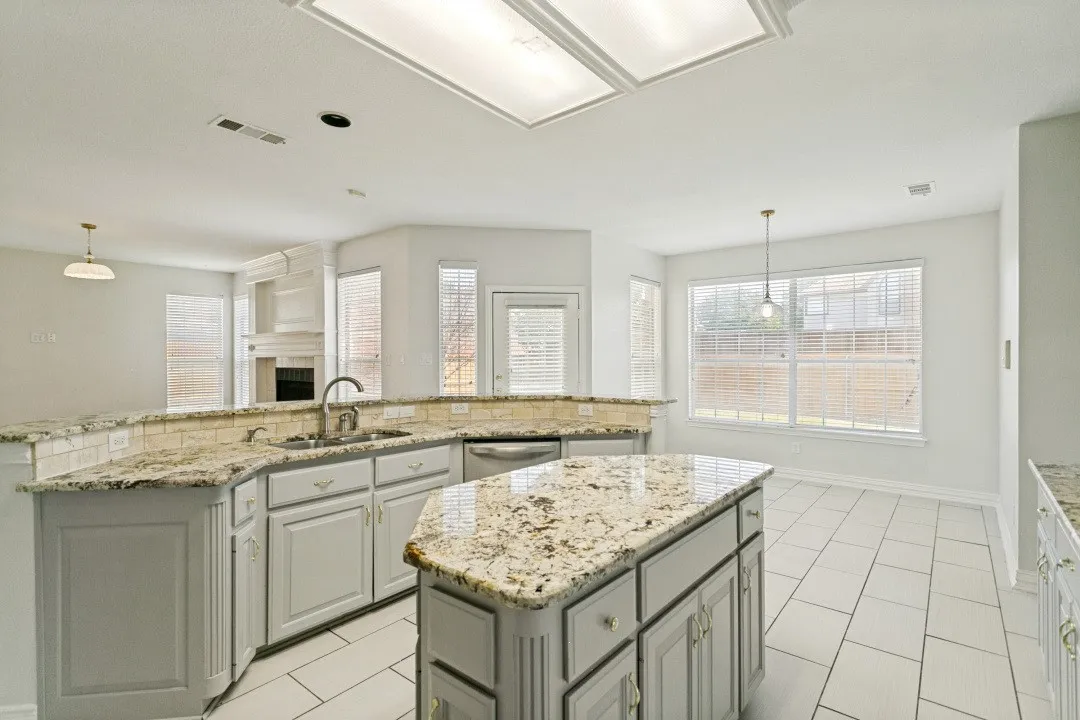 Kitchen featuring a central island with countertop, coordinating perimeter countertops with a tile backsplash, light-toned cabinetry, and stainless steel appliances