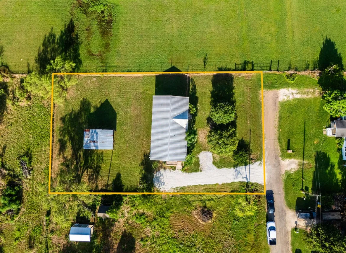 Aerial view of property featuring a single-story structure with a metal roof and a detached shed