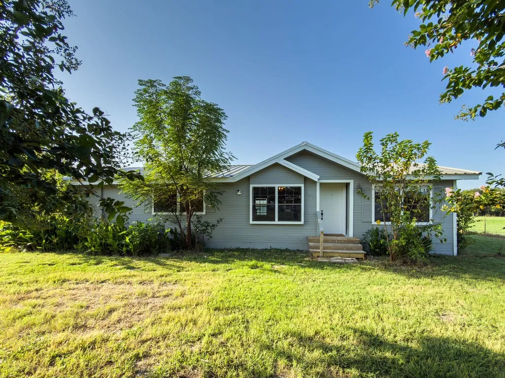 Light gray siding exterior with white trim, featuring a white entry door and a covered entryway