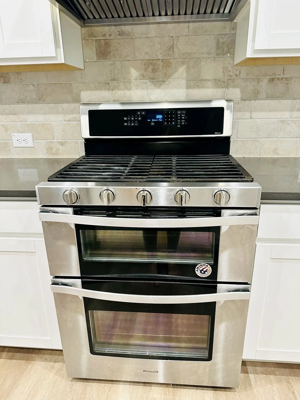 Kitchen with light hardwood / wood-style floors, tasteful backsplash, white cabinetry, double oven range, and premium range hood
