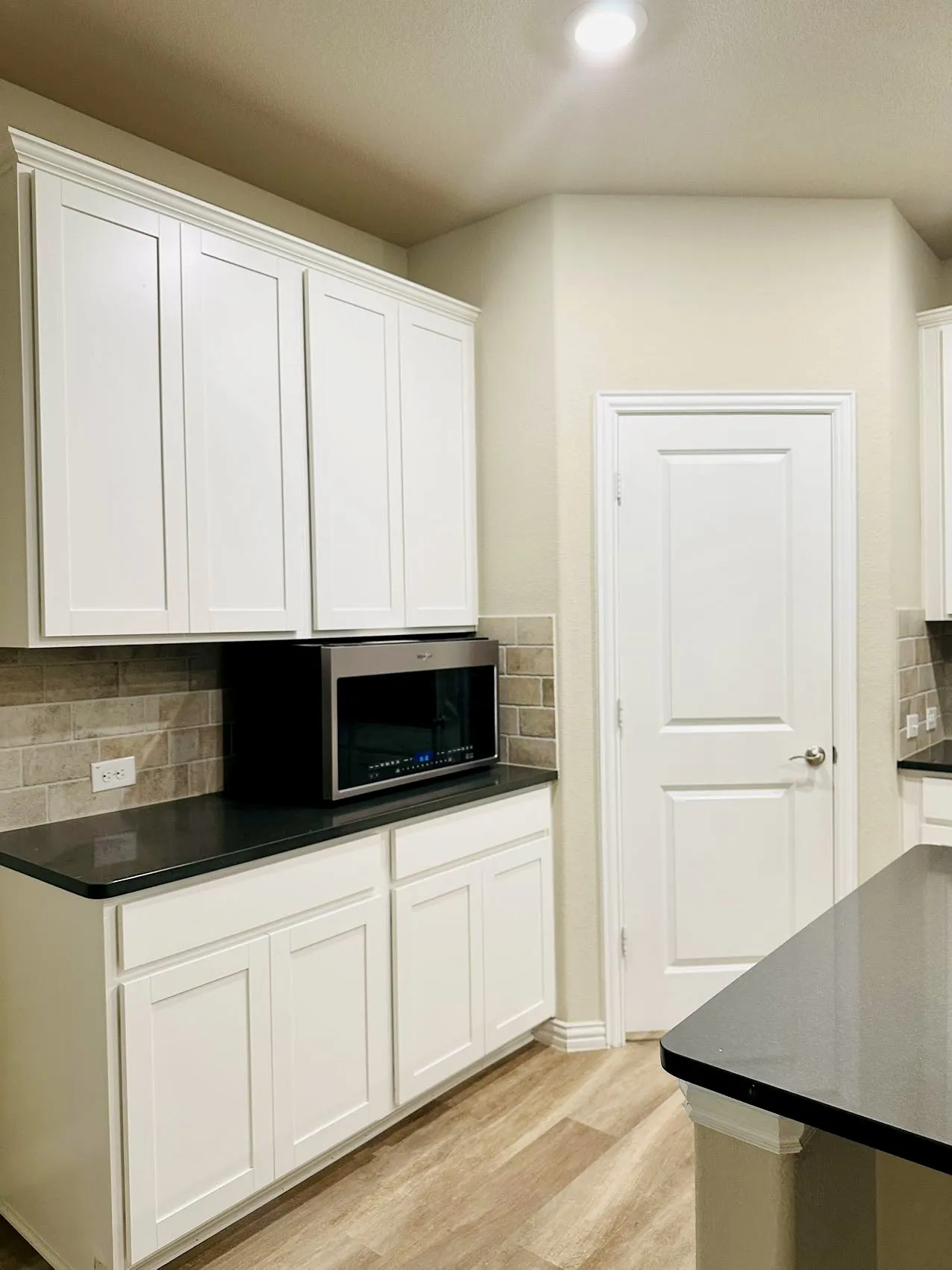 Kitchen featuring light hardwood / wood-style floors, tasteful backsplash, and white cabinetry