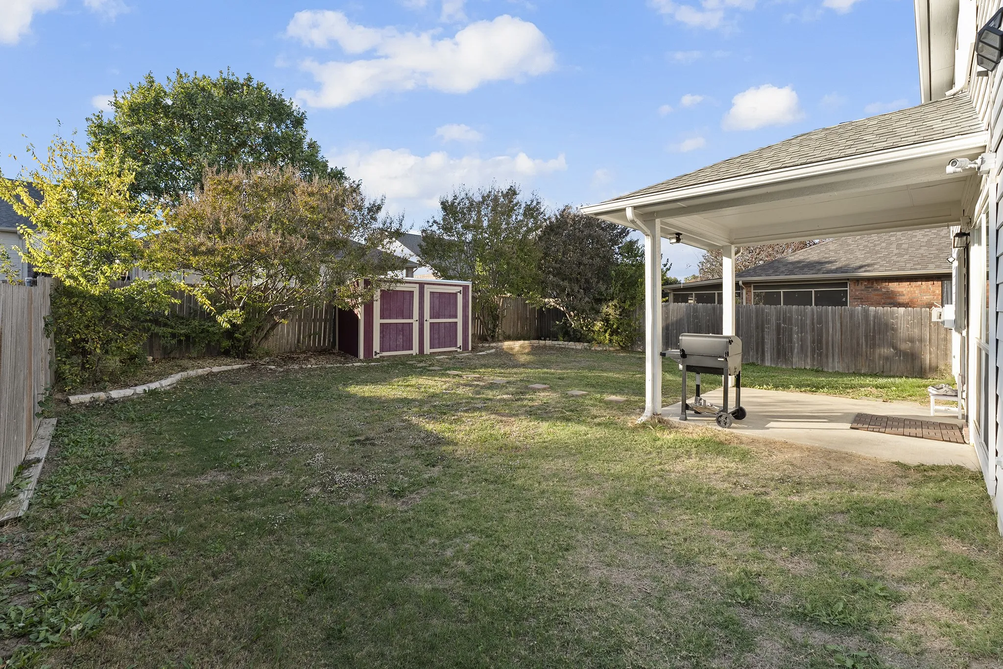 Fenced backyard featuring a patio area and a shed