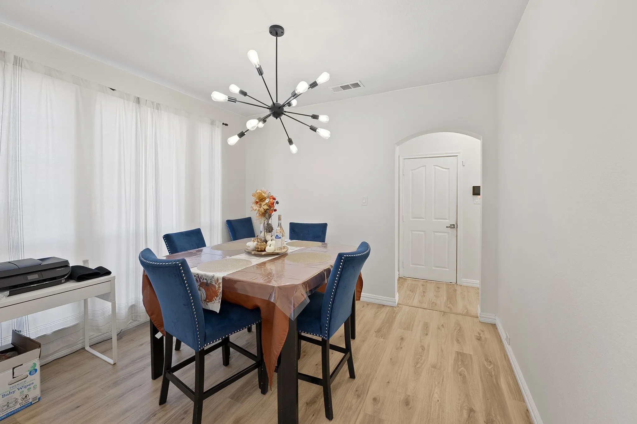 Dining area featuring arched walkways, light wood finished floors, and a chandelier