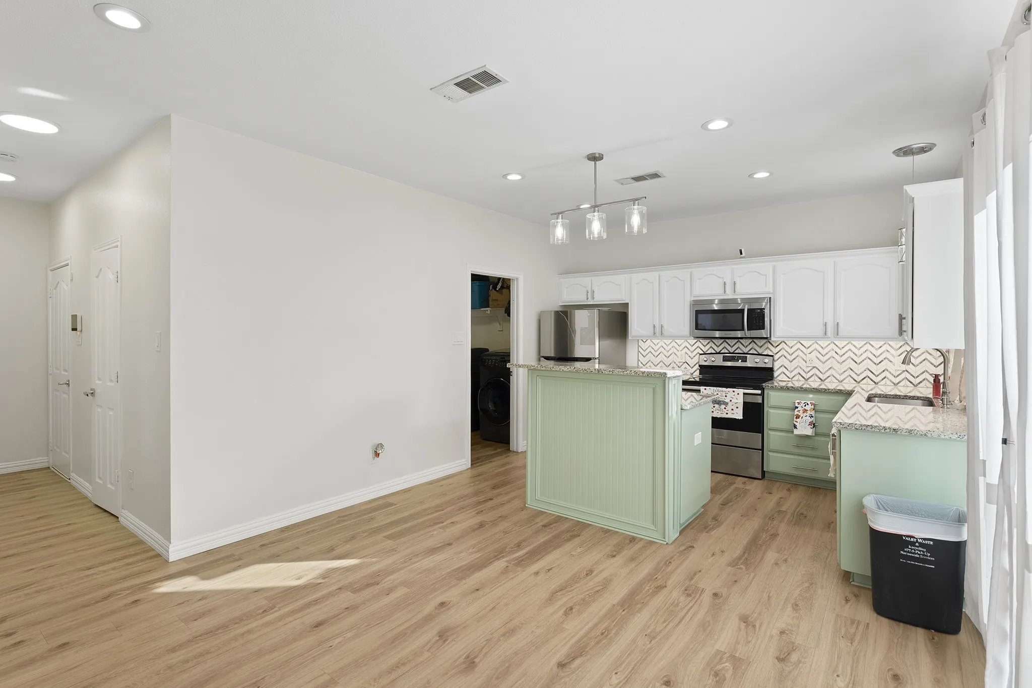 Kitchen with green cabinets, white cabinets, pendant lighting, recessed lighting, and light stone countertops