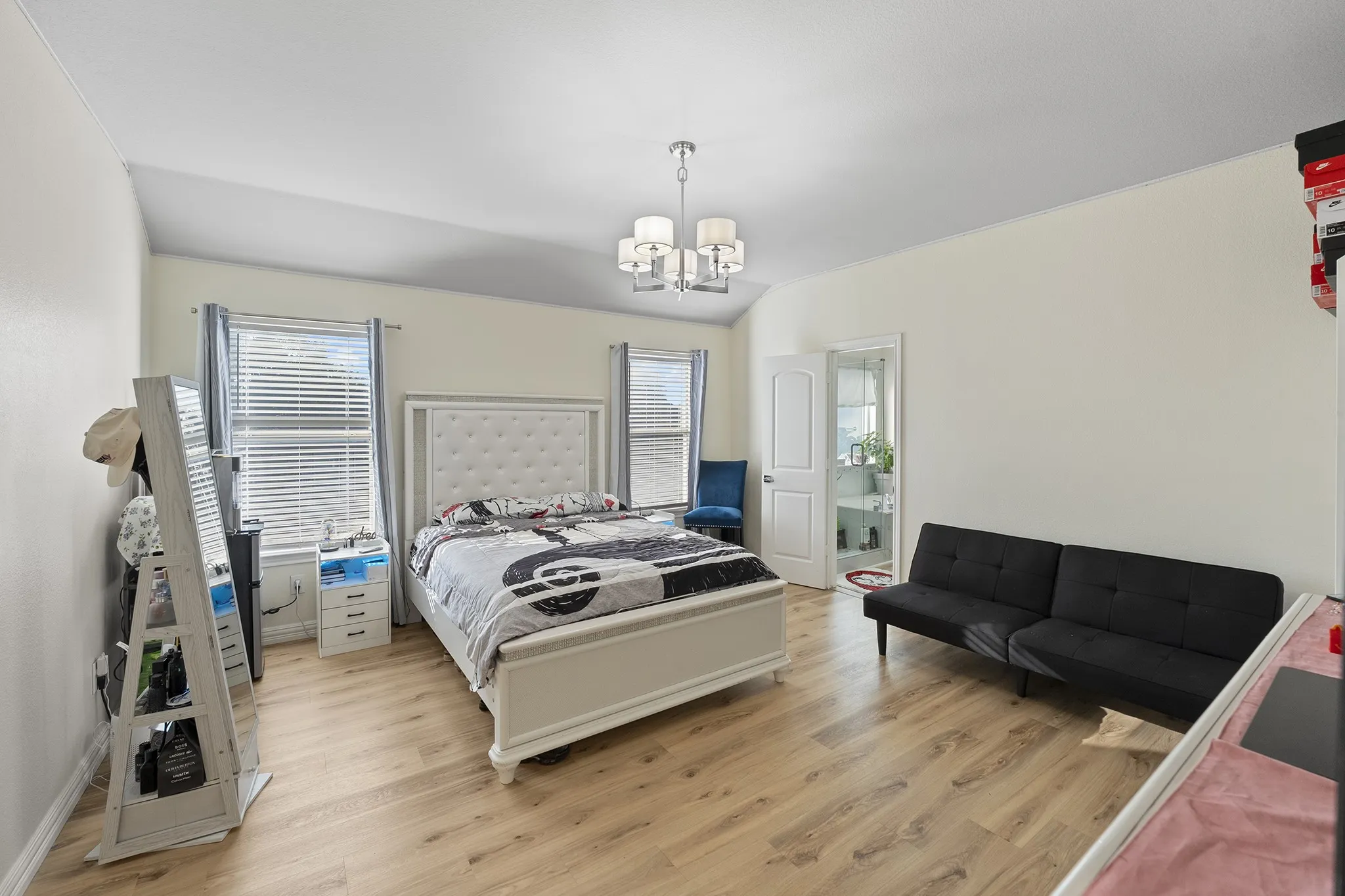 Bedroom with light wood-style floors, multiple windows, a chandelier, and lofted ceiling