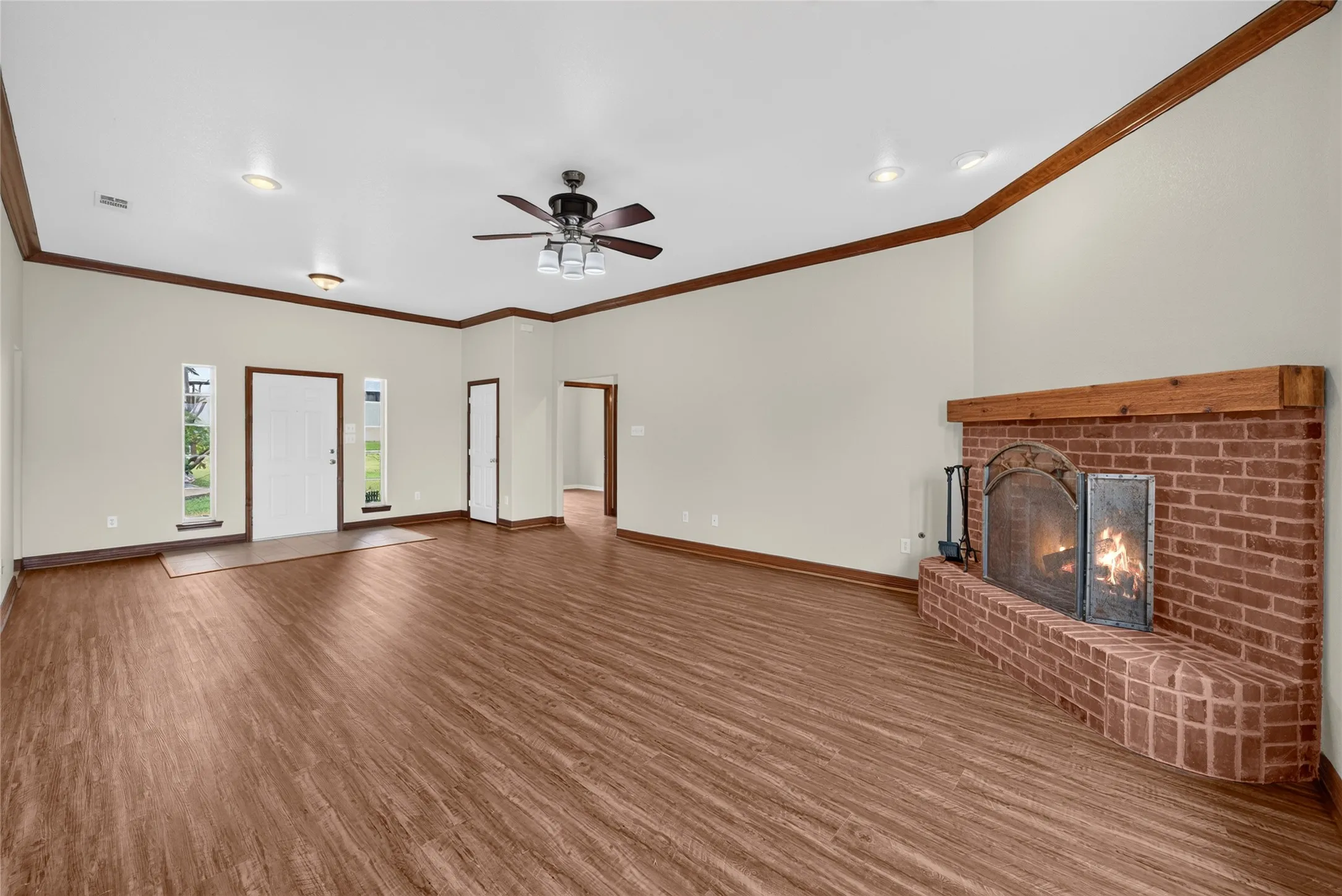 Spacious living area featuring a brick fireplace with a wood mantel