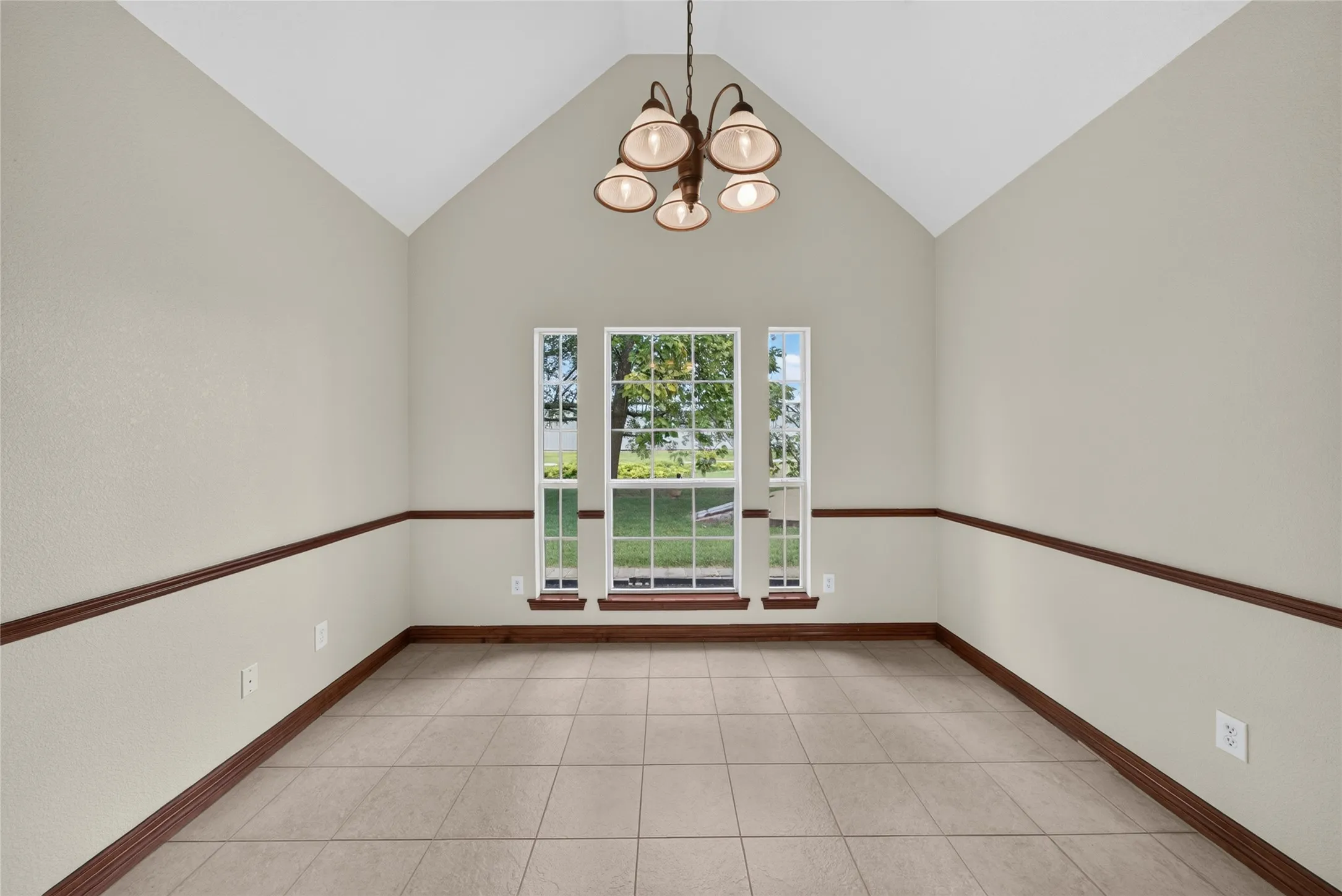 Formal dining space featuring a vaulted ceiling and tile flooring