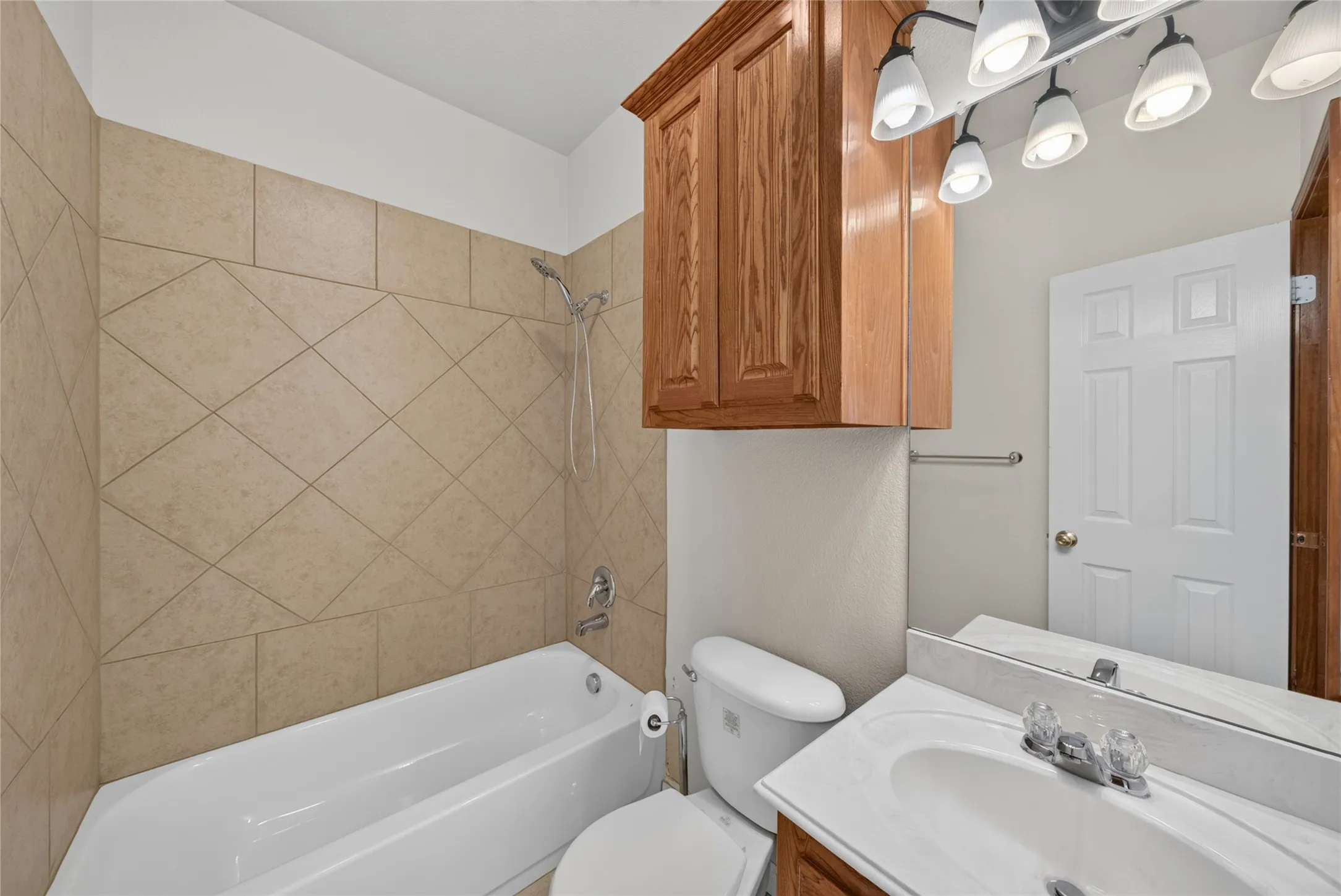 Bathroom featuring a white bathtub, ceramic tile surround with diagonal pattern, and a chrome shower head
