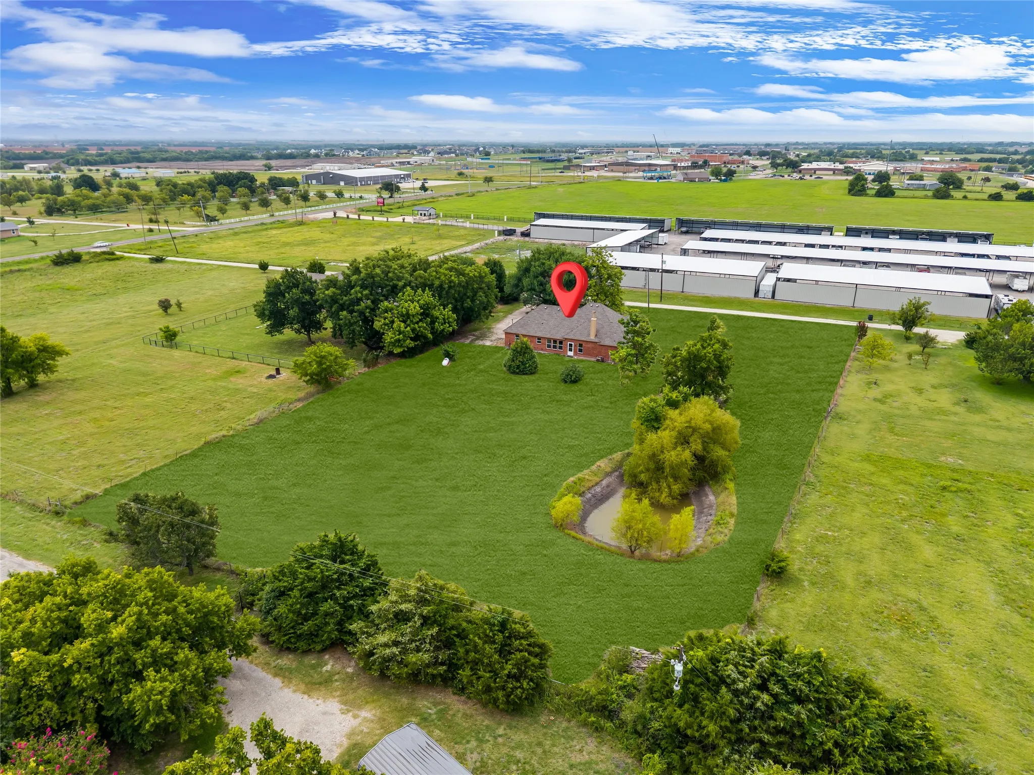 Expansive property featuring a single-story brick residence with a gabled roof, surrounded by extensive green lawn