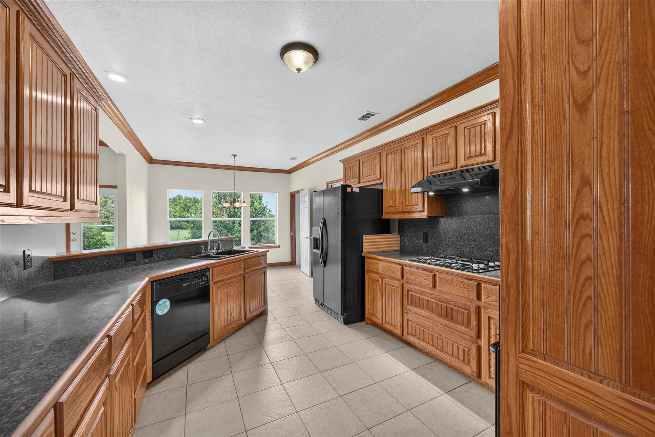 Expansive kitchen featuring wood cabinetry, stone countertops, and tile flooring