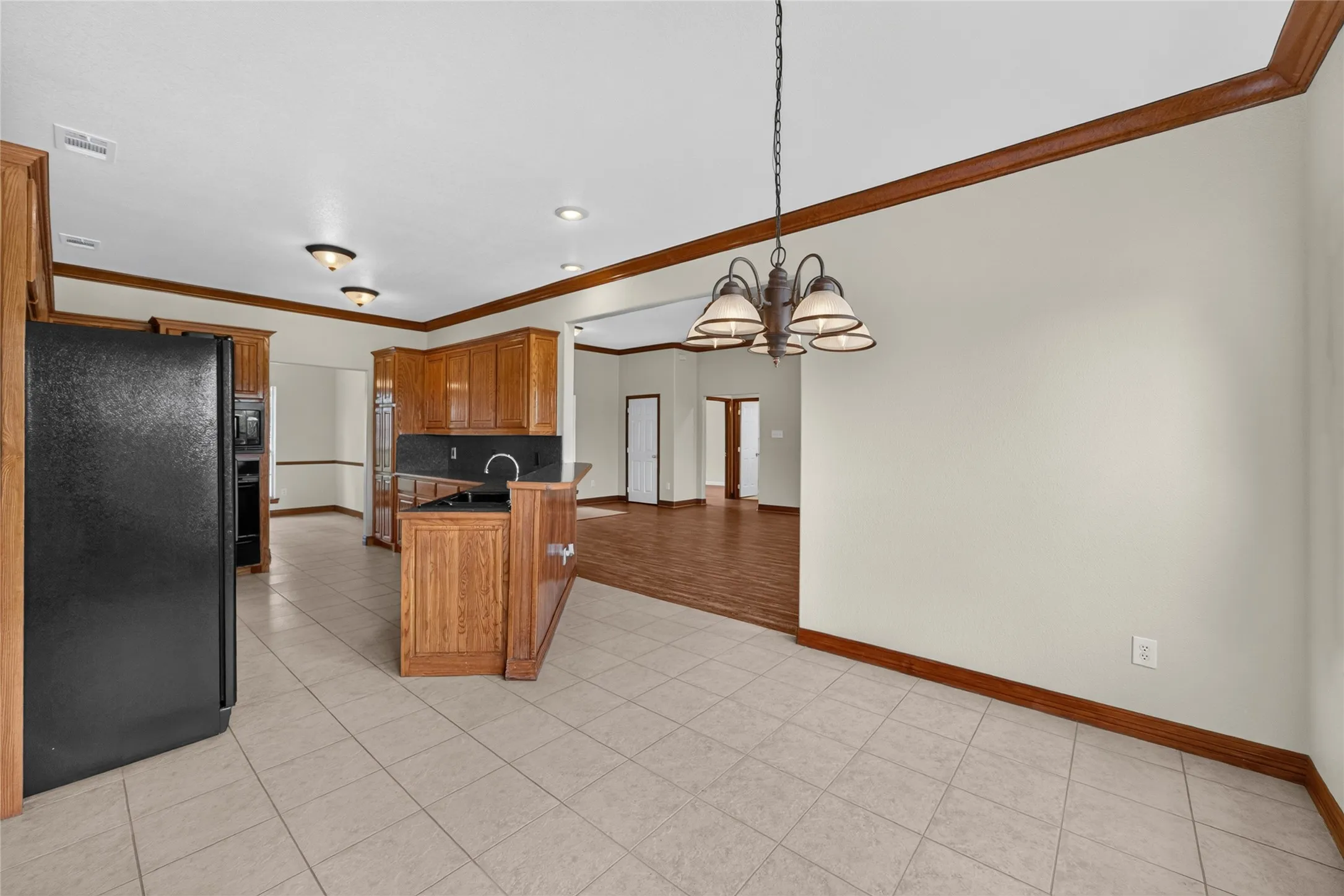 Kitchen and dining area featuring light-toned tile flooring and a bronze chandelier