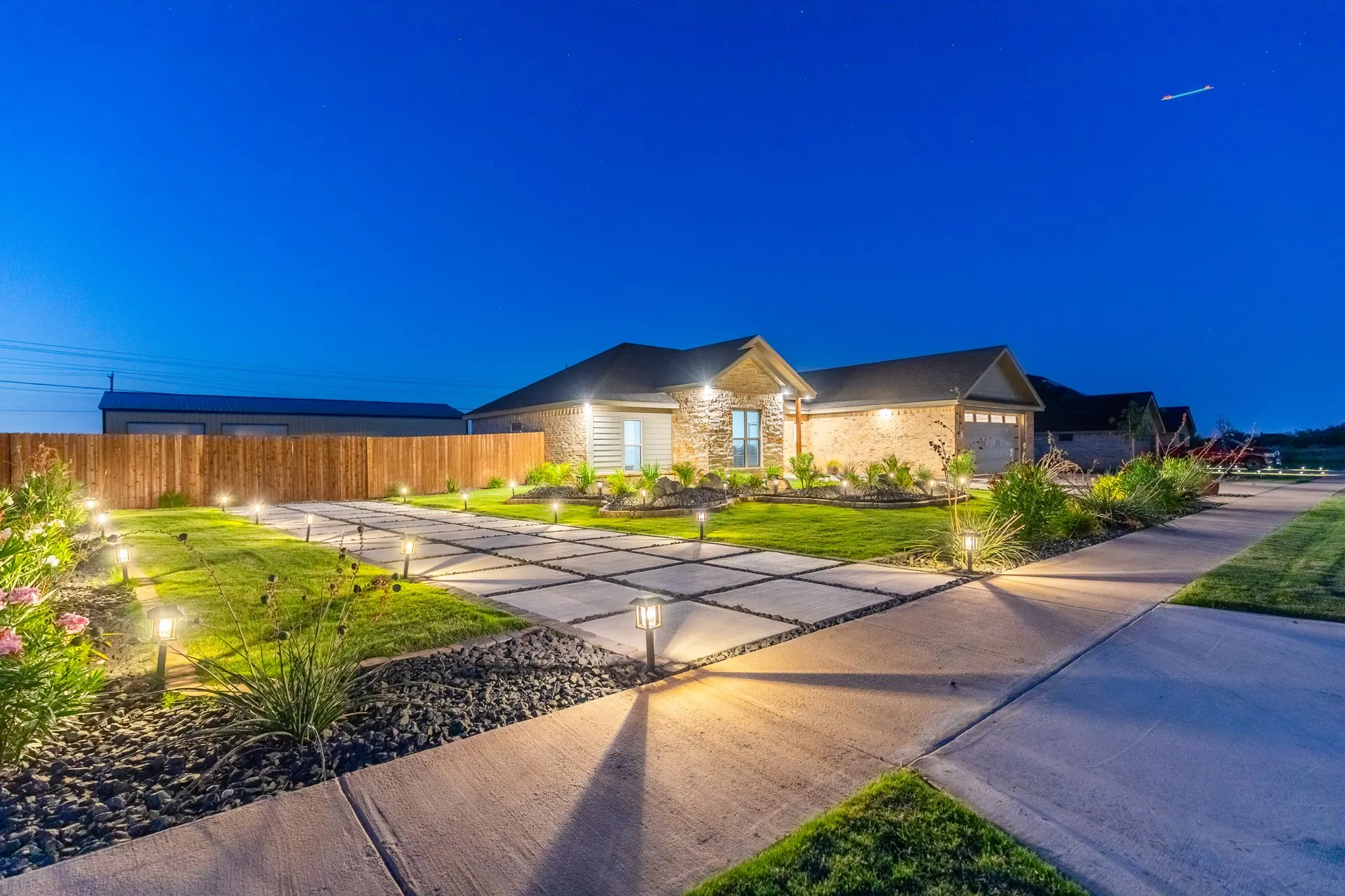 Exterior featuring a stone and siding facade, an attached two-car garage, and a wood privacy fence