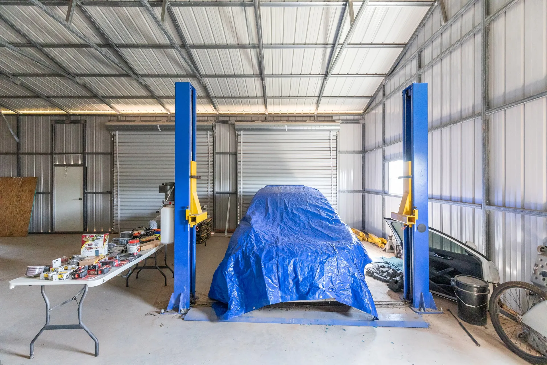 Spacious garage facility featuring concrete flooring, corrugated metal walls, and a high-pitched metal ceiling