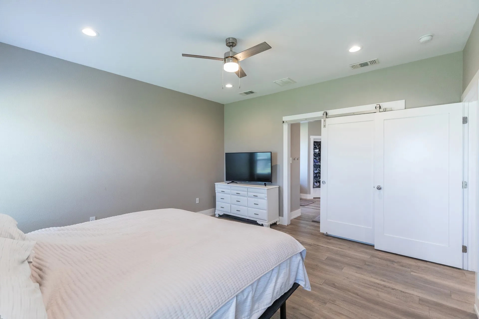 Spacious room featuring wood-finish flooring, recessed lighting, and a ceiling fan