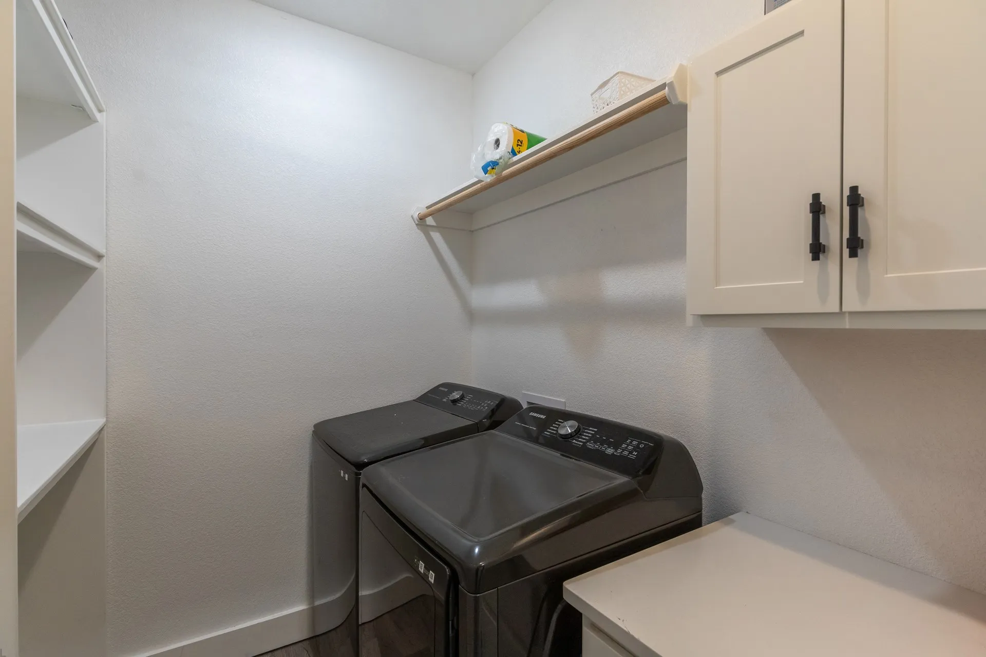 Dedicated laundry space featuring built-in cabinetry, an integrated countertop, and a wood-finish shelf