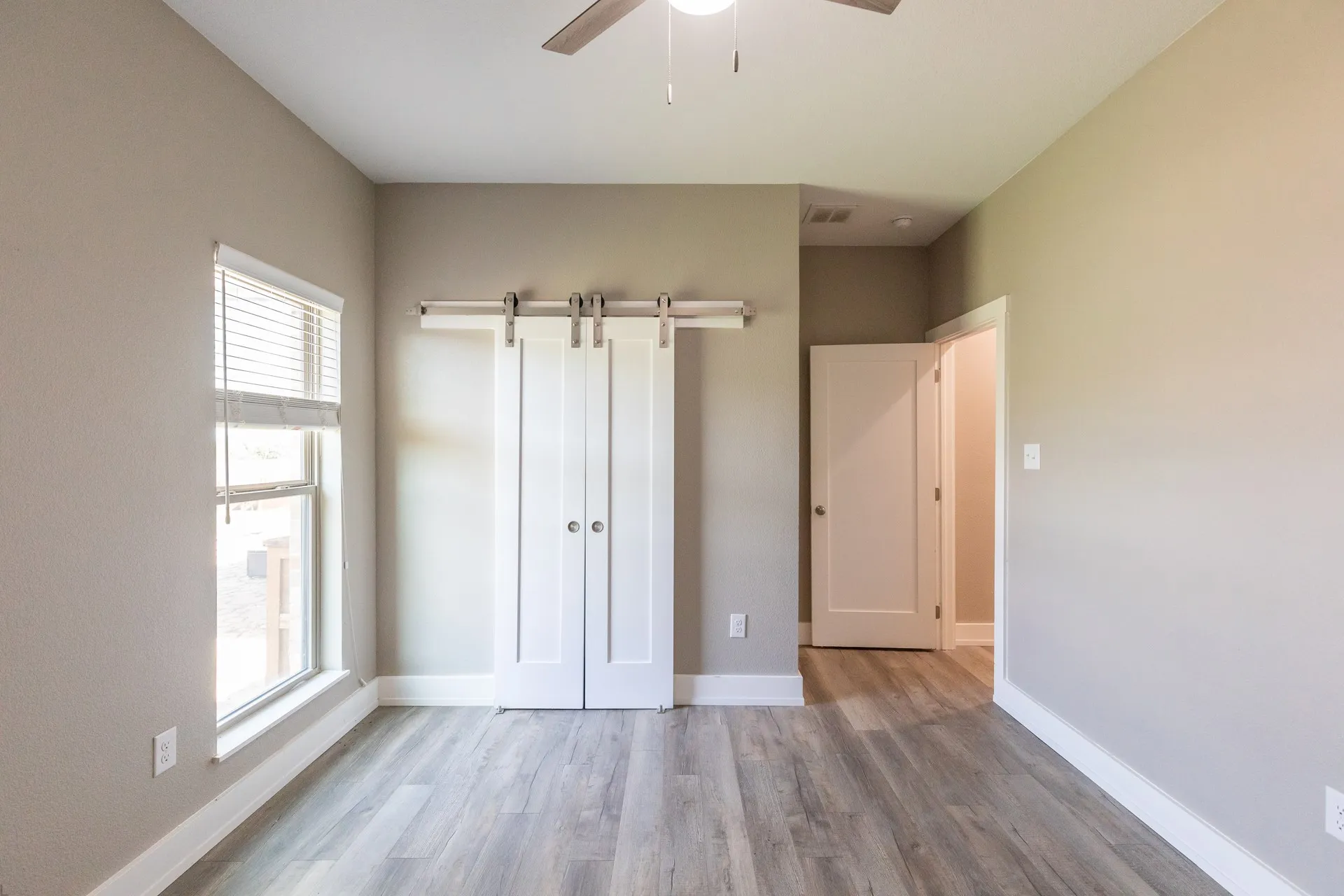 Neutral-toned interior featuring wood-finish flooring and a white barn door system