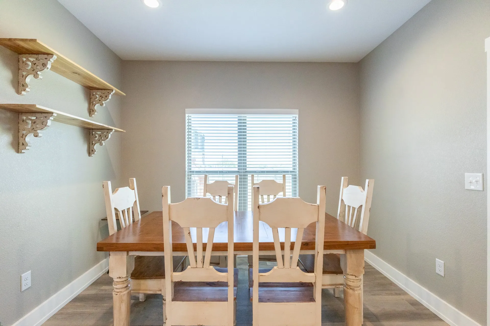 Dining area featuring wood-finish flooring, two decorative floating shelves, and recessed ceiling lighting