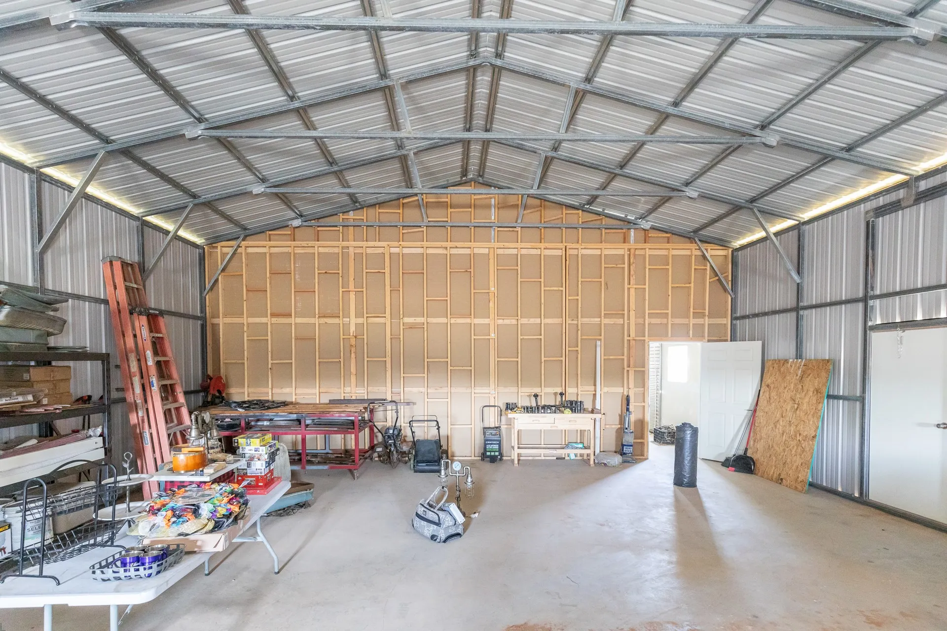 Spacious metal-sided structure featuring a high-pitched metal roof, exposed steel framing, and a concrete floor