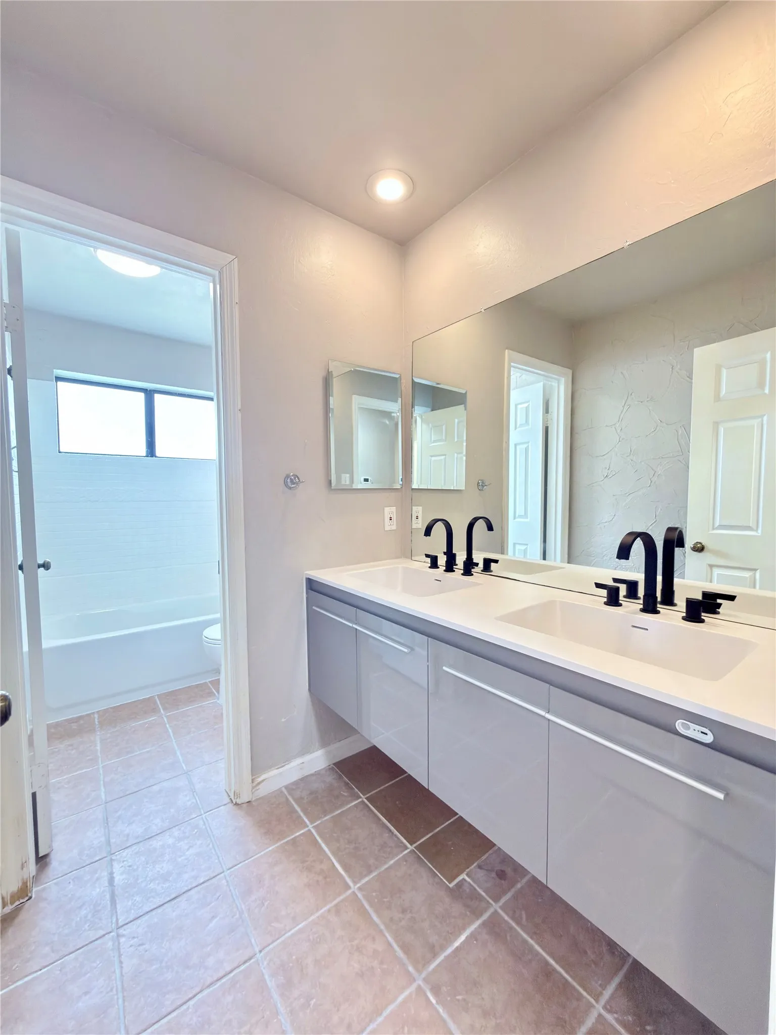 Floating dual vanity with integrated white sinks, matte black faucets, and a full-width mirror