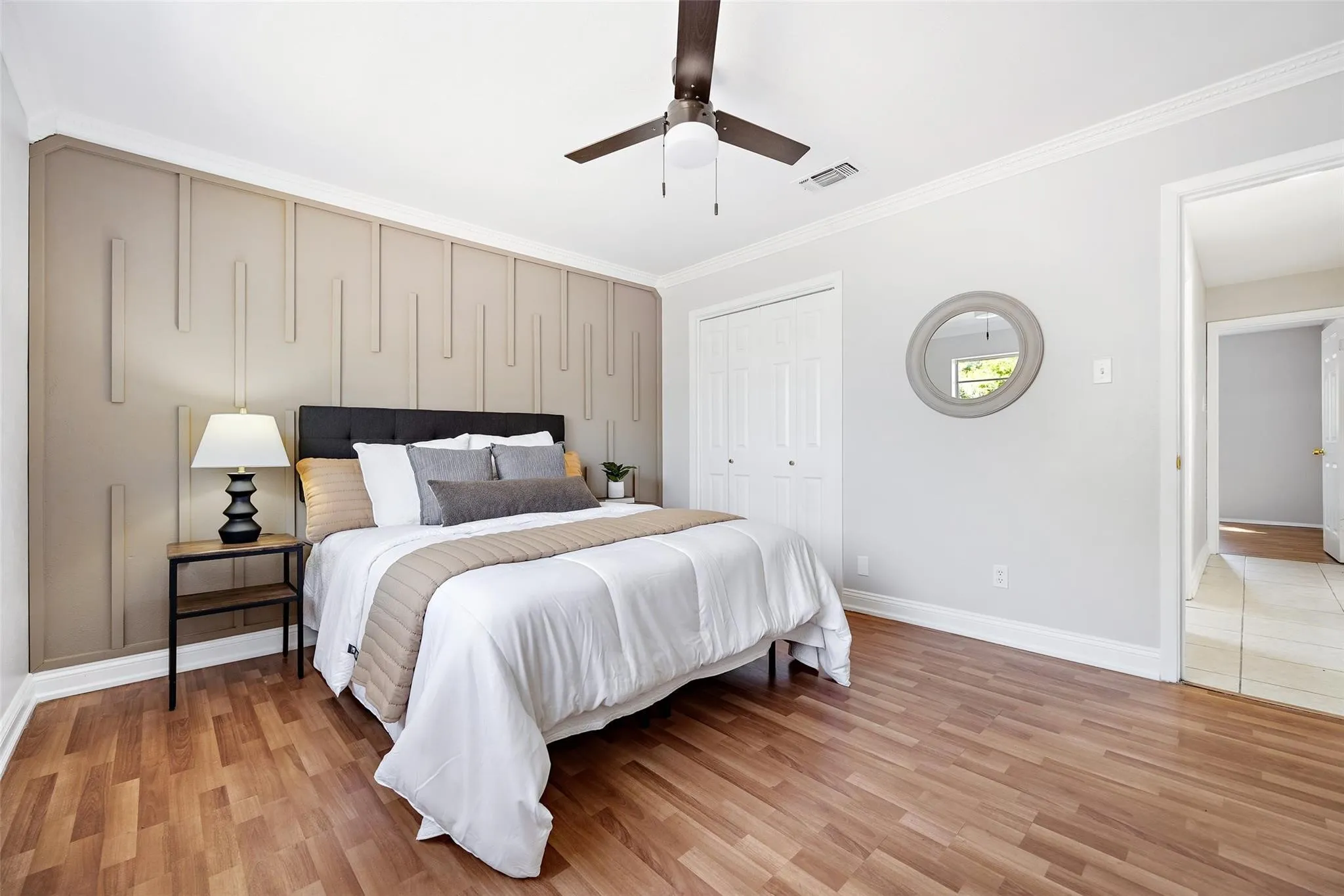 Bedroom featuring a textured accent wall, wood-finish flooring, ceiling fan, and bi-fold closet doors virtual Staged picture
