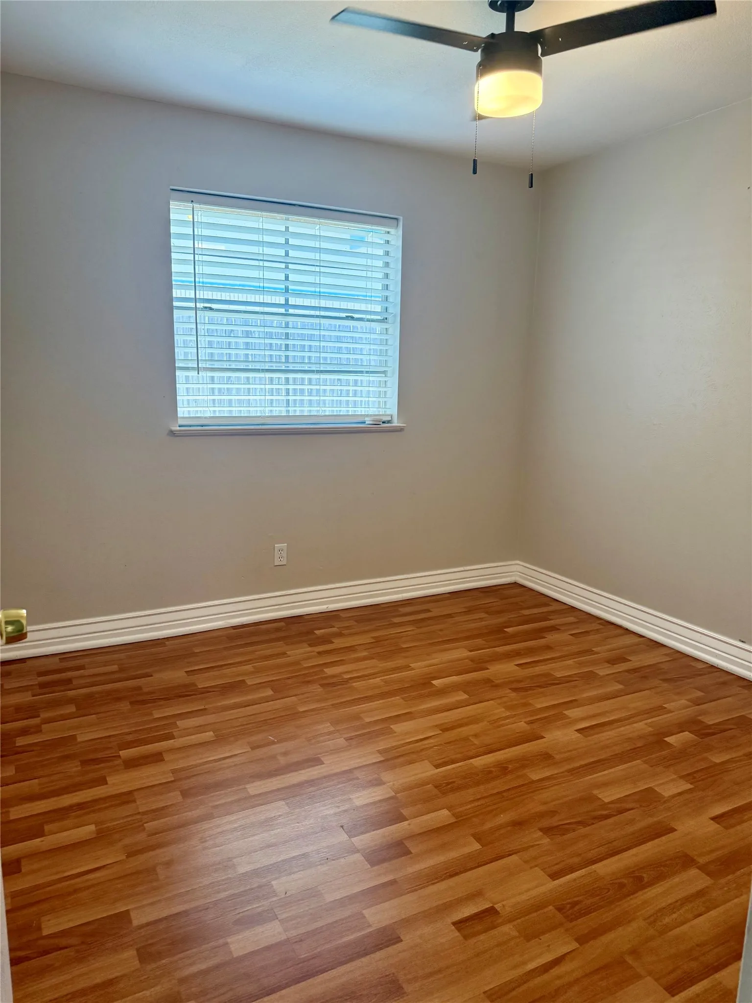 Room featuring wood-finish flooring, a window with blinds, a ceiling fan with integrated lighting, and white baseboard molding