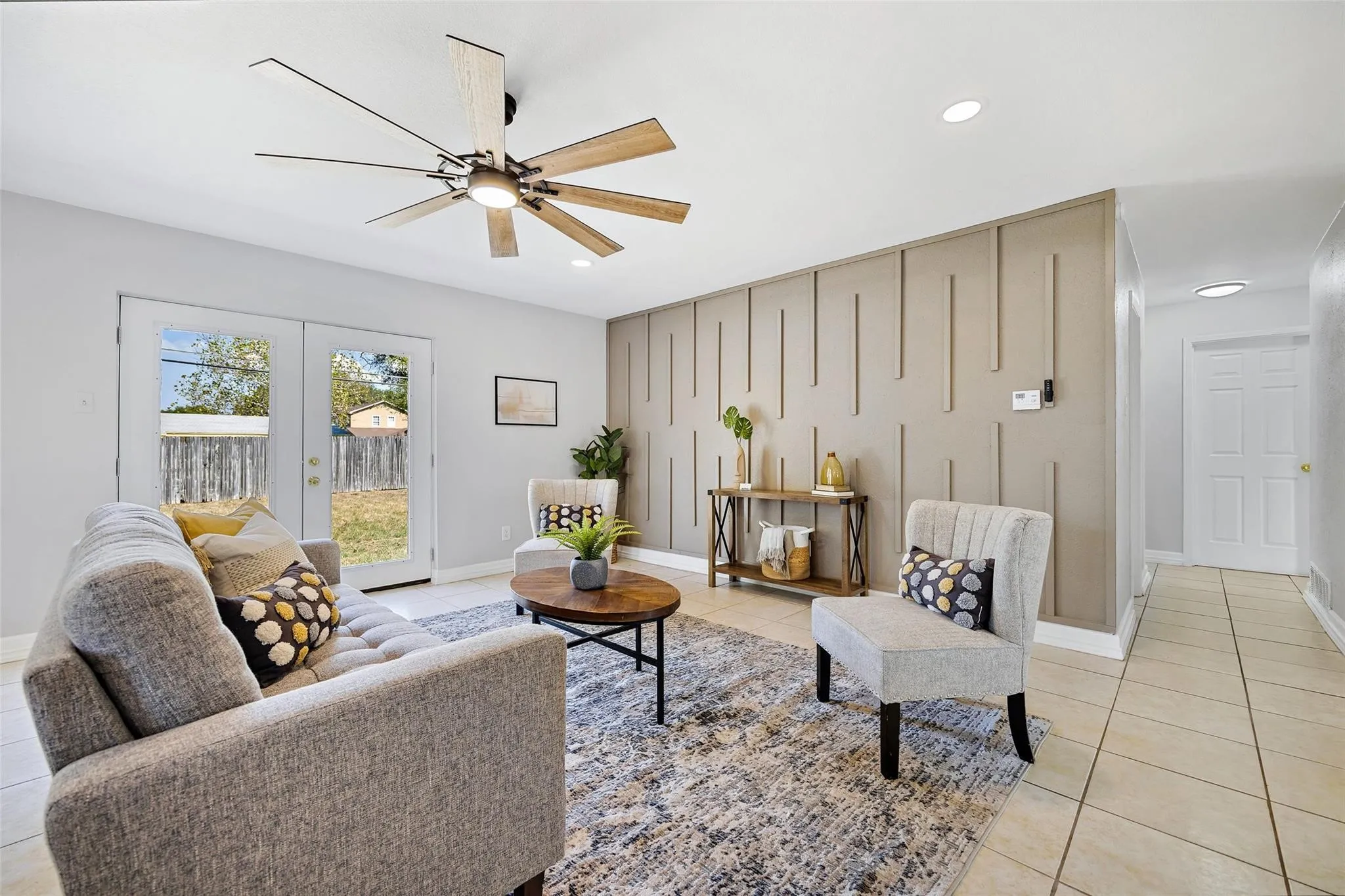 Living area featuring a contemporary ceiling fan, recessed lighting, and a textured accent wall virtual staging