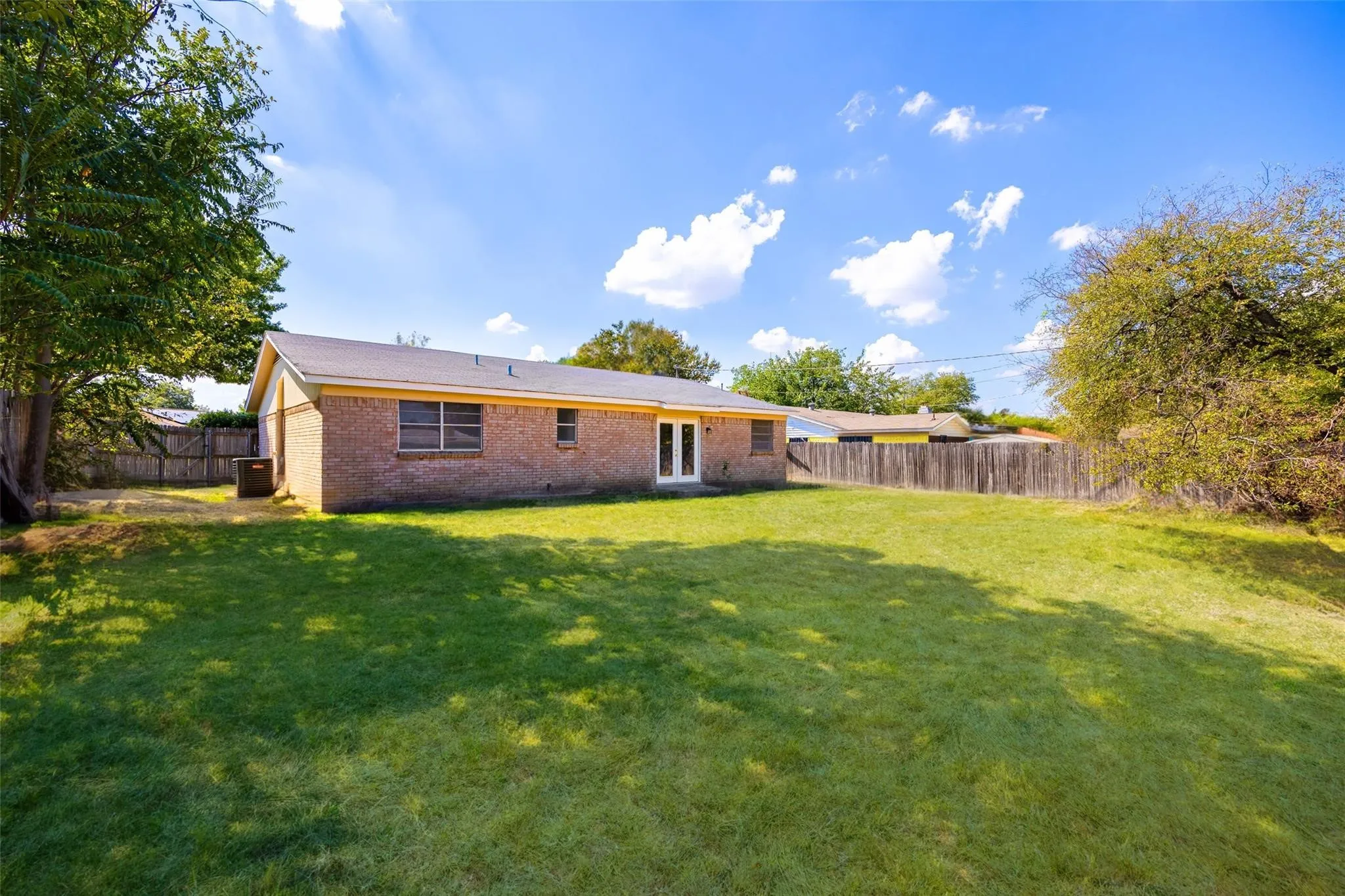 Expansive green lawn with mature trees and a brick exterior