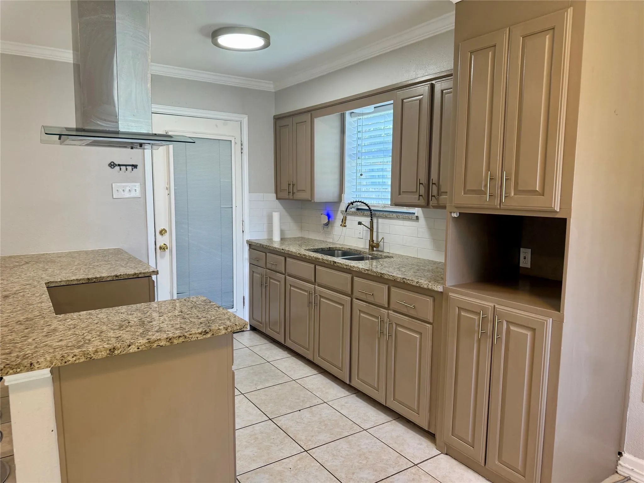 Spacious kitchen featuring extensive cabinetry, stone-finish countertops, and a modern range hood