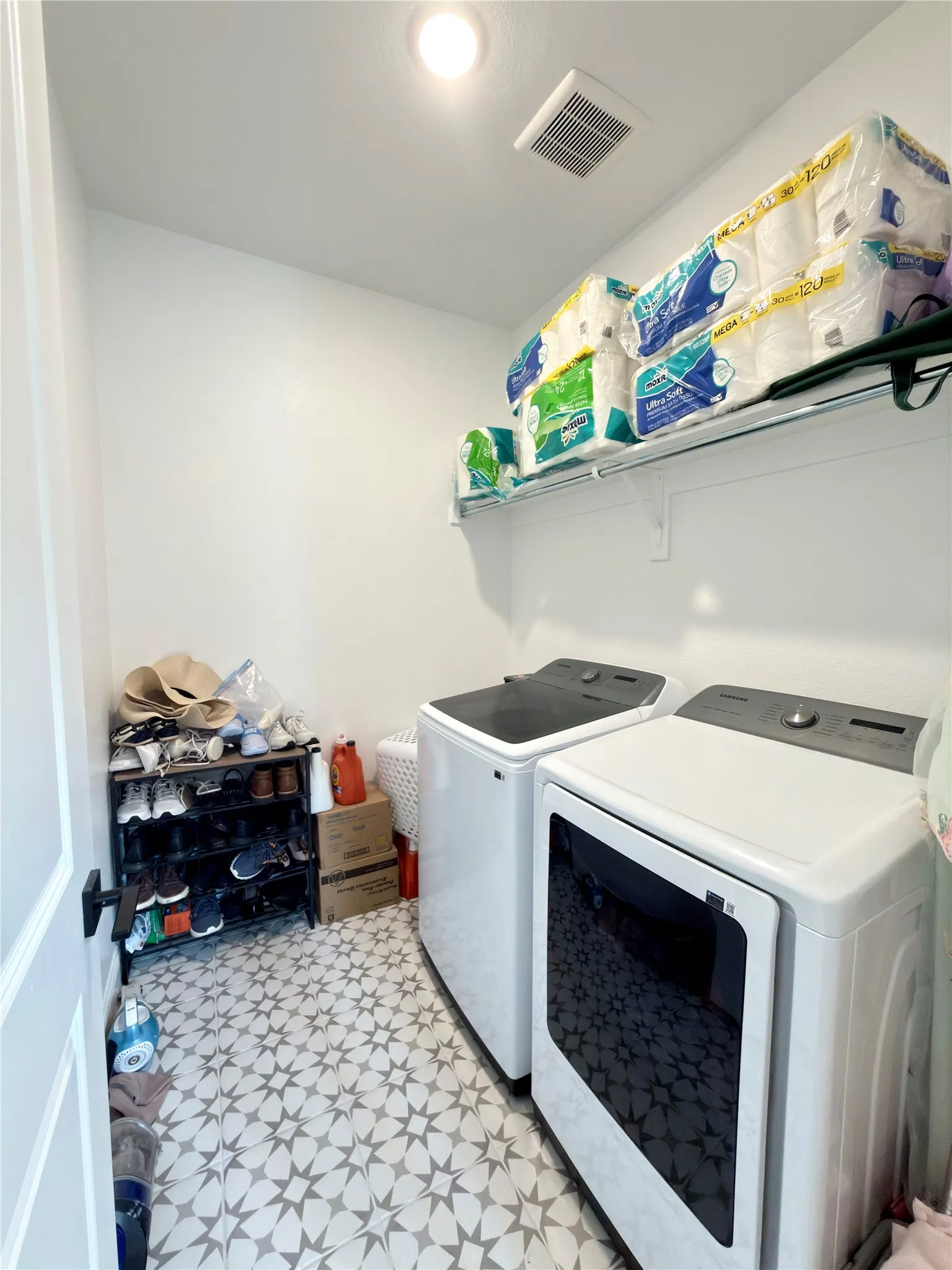 Dedicated laundry area featuring patterned tile flooring, a white ceiling, recessed lighting, and a wall-mounted storage shelf