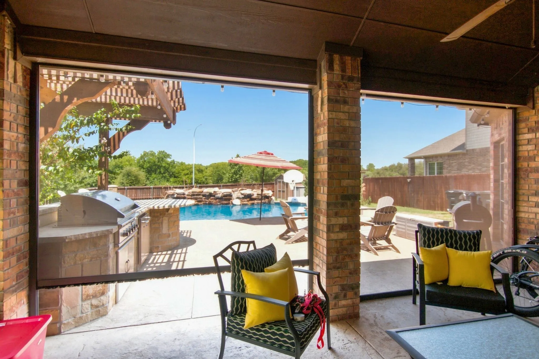 Outdoor covered patio featuring brick columns, retractable screens, and a ceiling fan