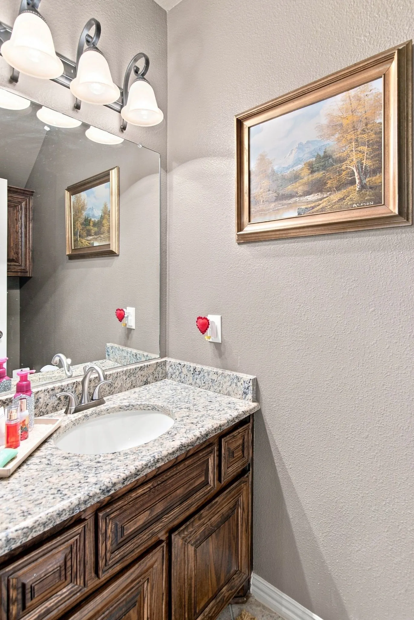 Bathroom featuring a built-in vanity with wood-finish cabinetry, a granite-finish countertop, and an undermount sink with a chrome faucet