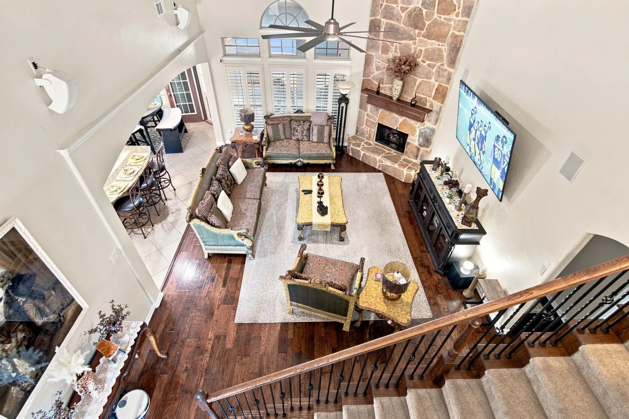 Soaring two-story great room with exposed wood-beam ceiling, brick fireplace, and abundant natural light from multiple windows