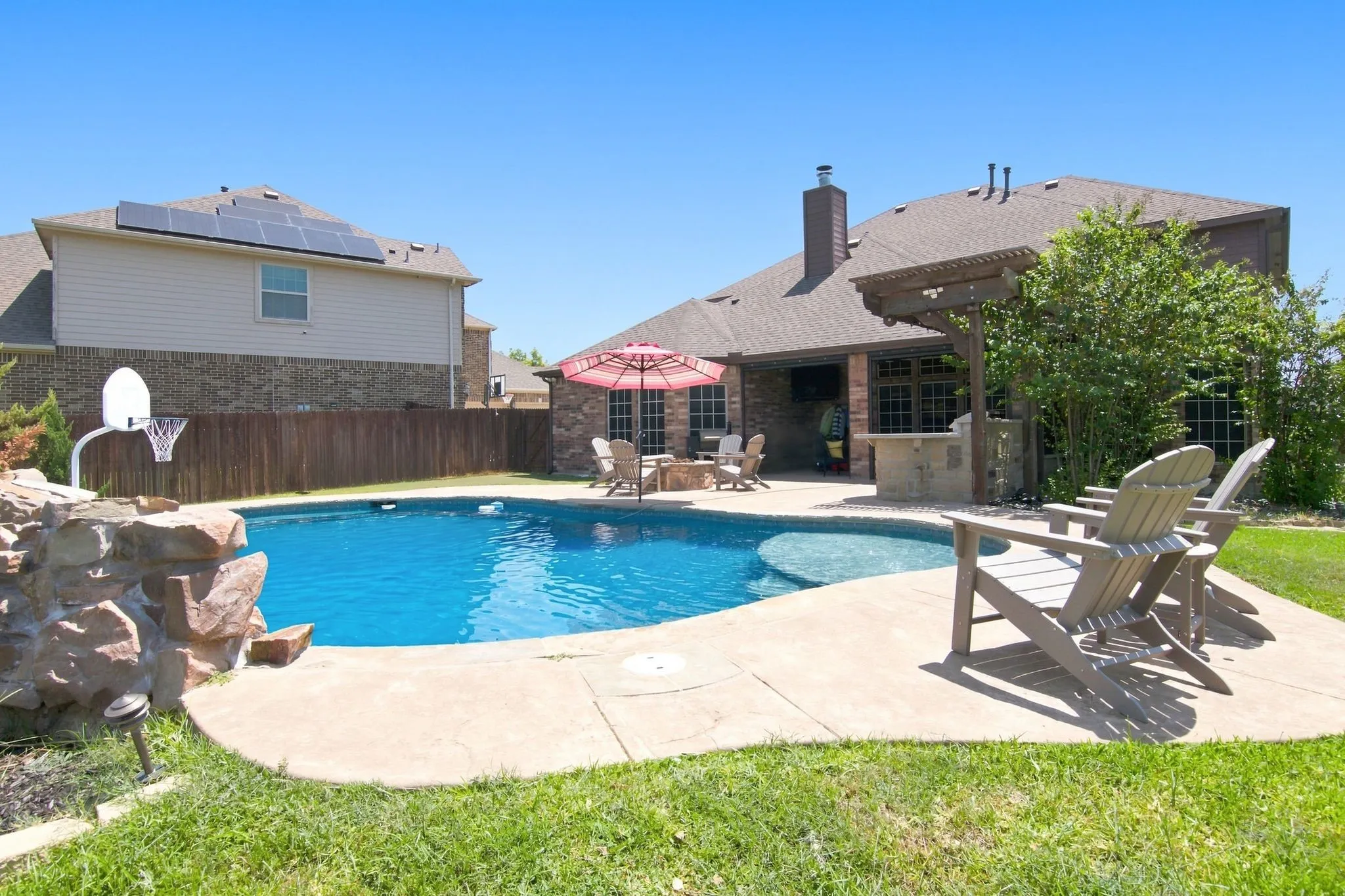 Backyard oasis featuring a swimming pool with an integrated spa and rock waterfall