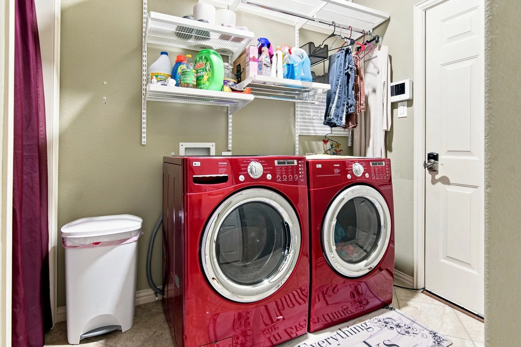 Utility area with wall-mounted shelving, a paneled interior door, and light-toned flooring