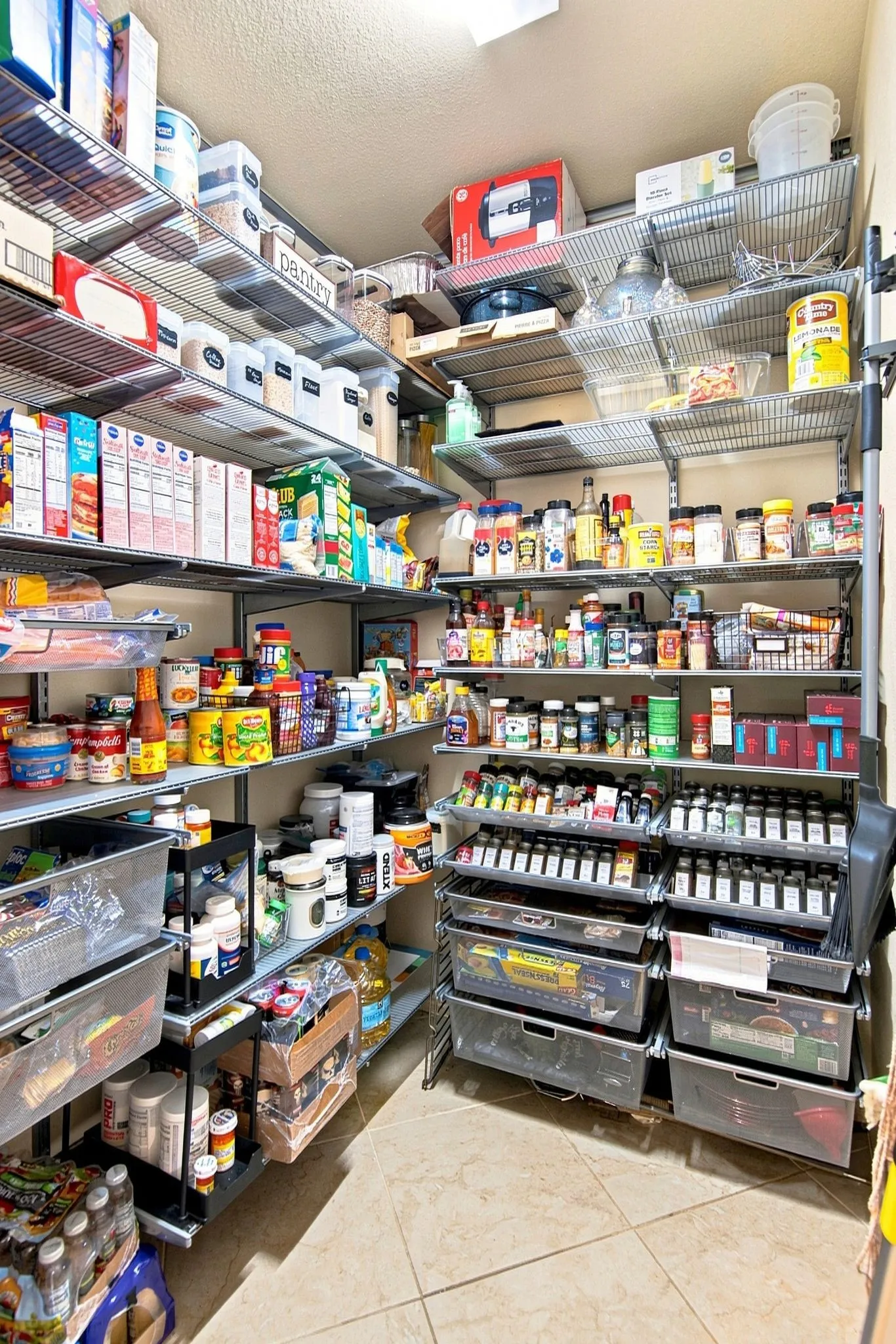 Walk-in pantry featuring extensive wire shelving, pull-out drawers, and tile flooring