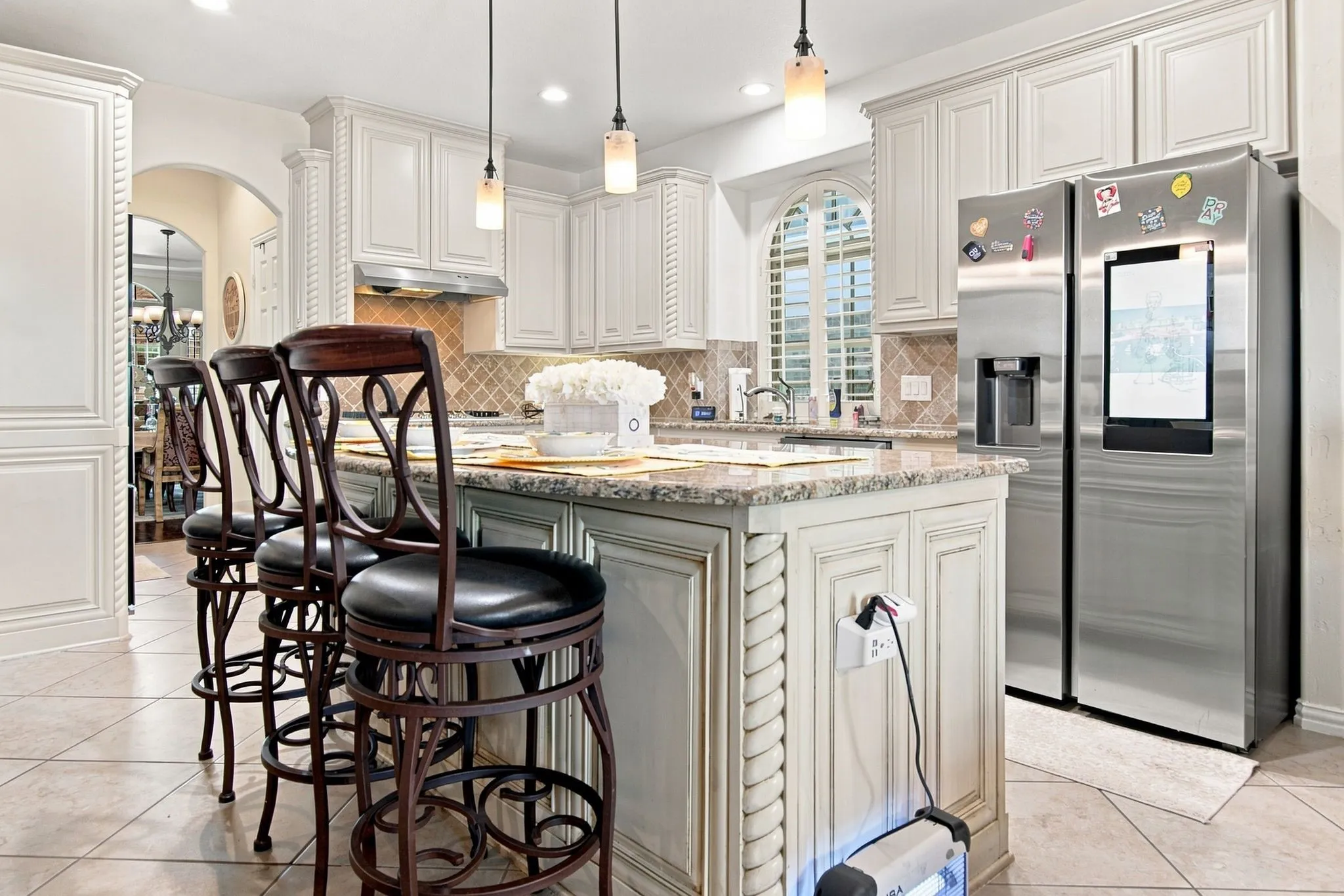 Kitchen island featuring a granite countertop, decorative carved wood accents, and pendant lighting
