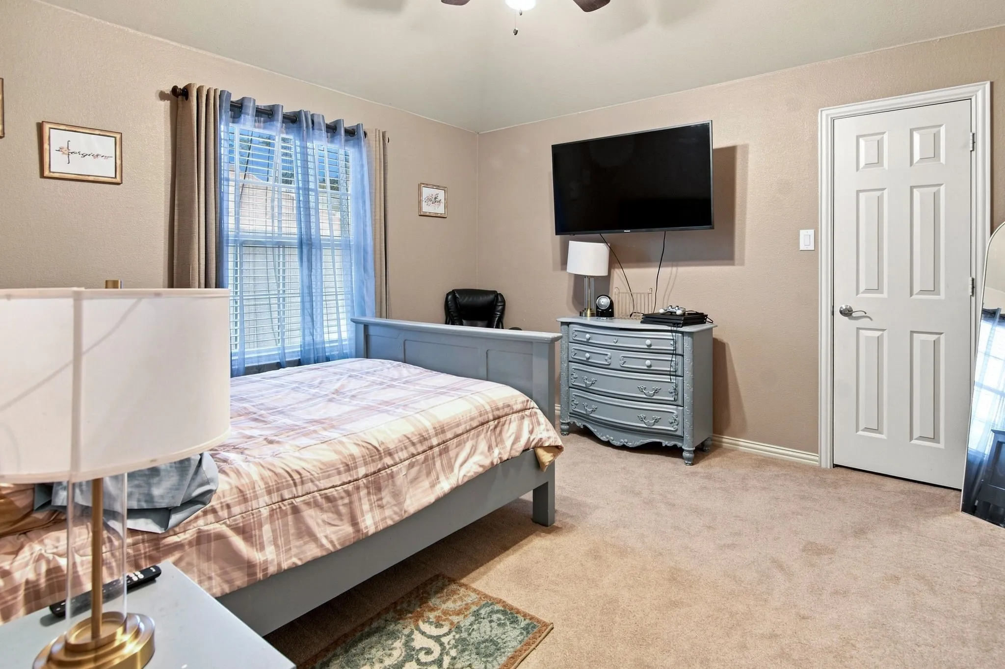Carpeted bedroom featuring a ceiling fan, a window with horizontal blinds, and a paneled door