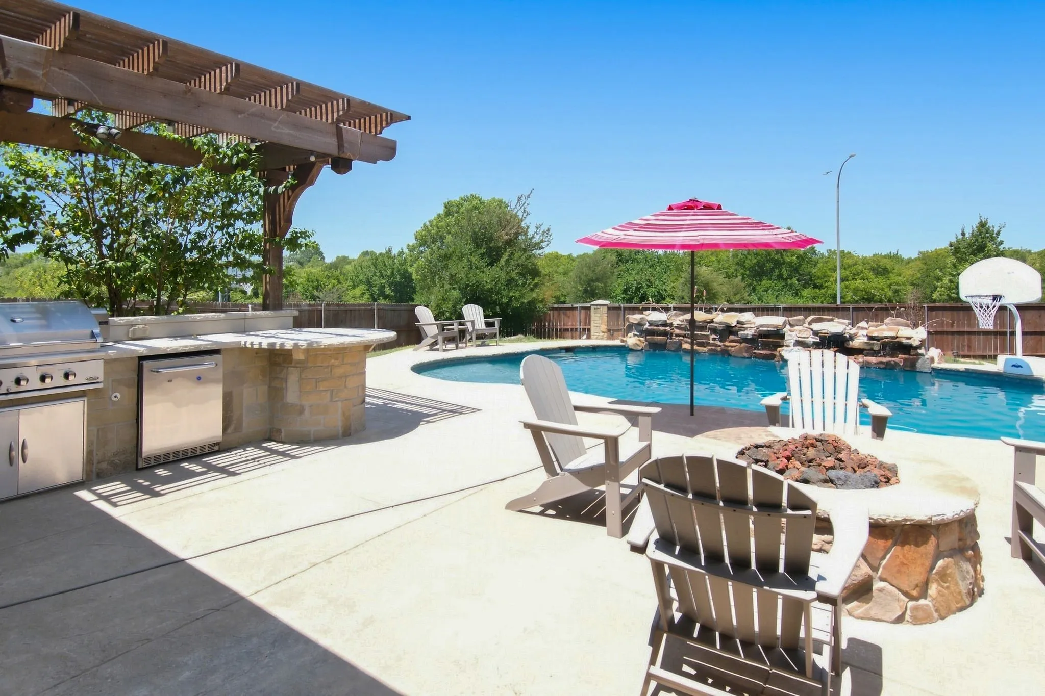 Outdoor living area featuring a custom stone fire pit and a curved swimming pool with a rock waterfall