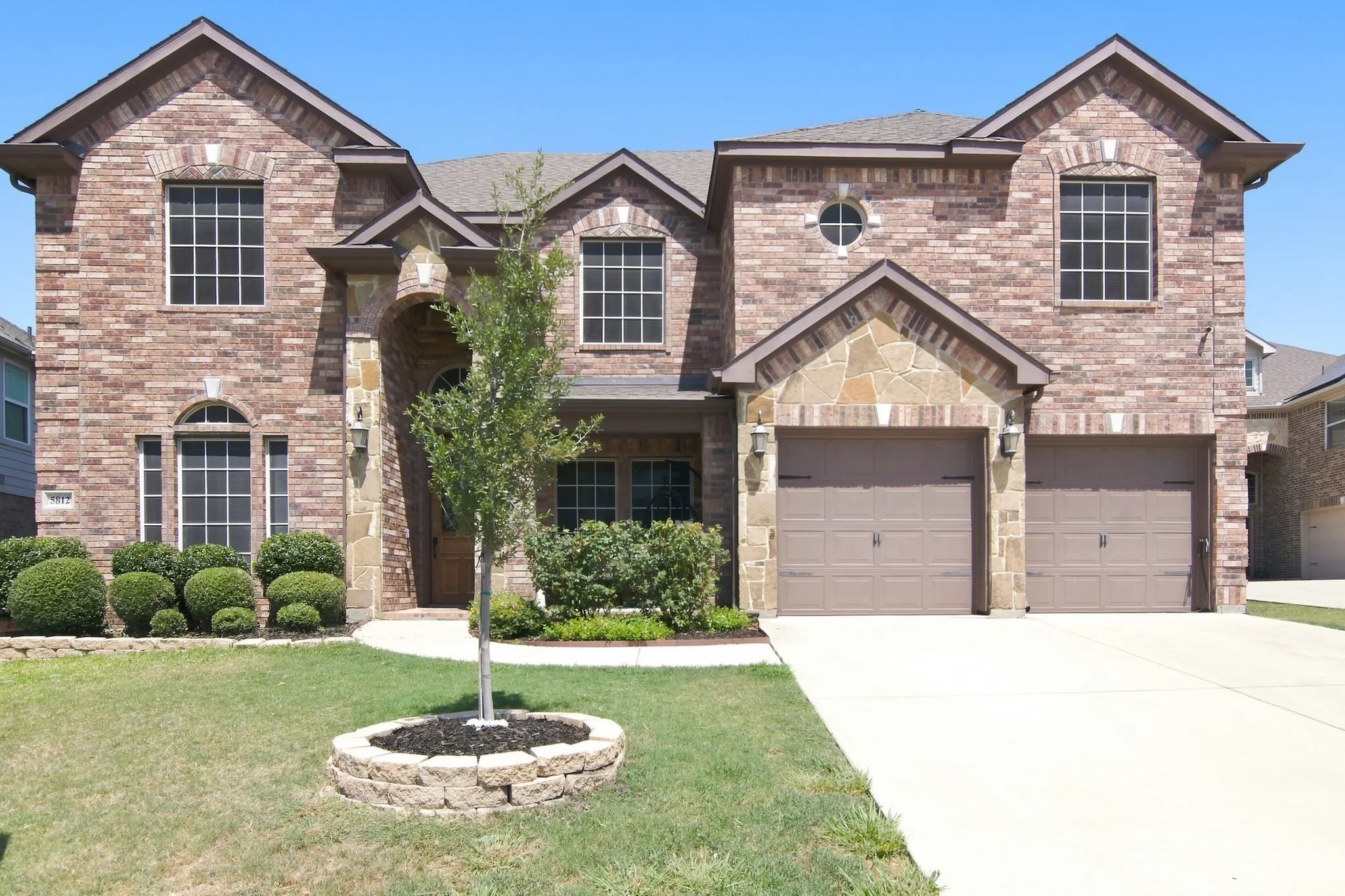 Brick and stone facade featuring a two-car garage