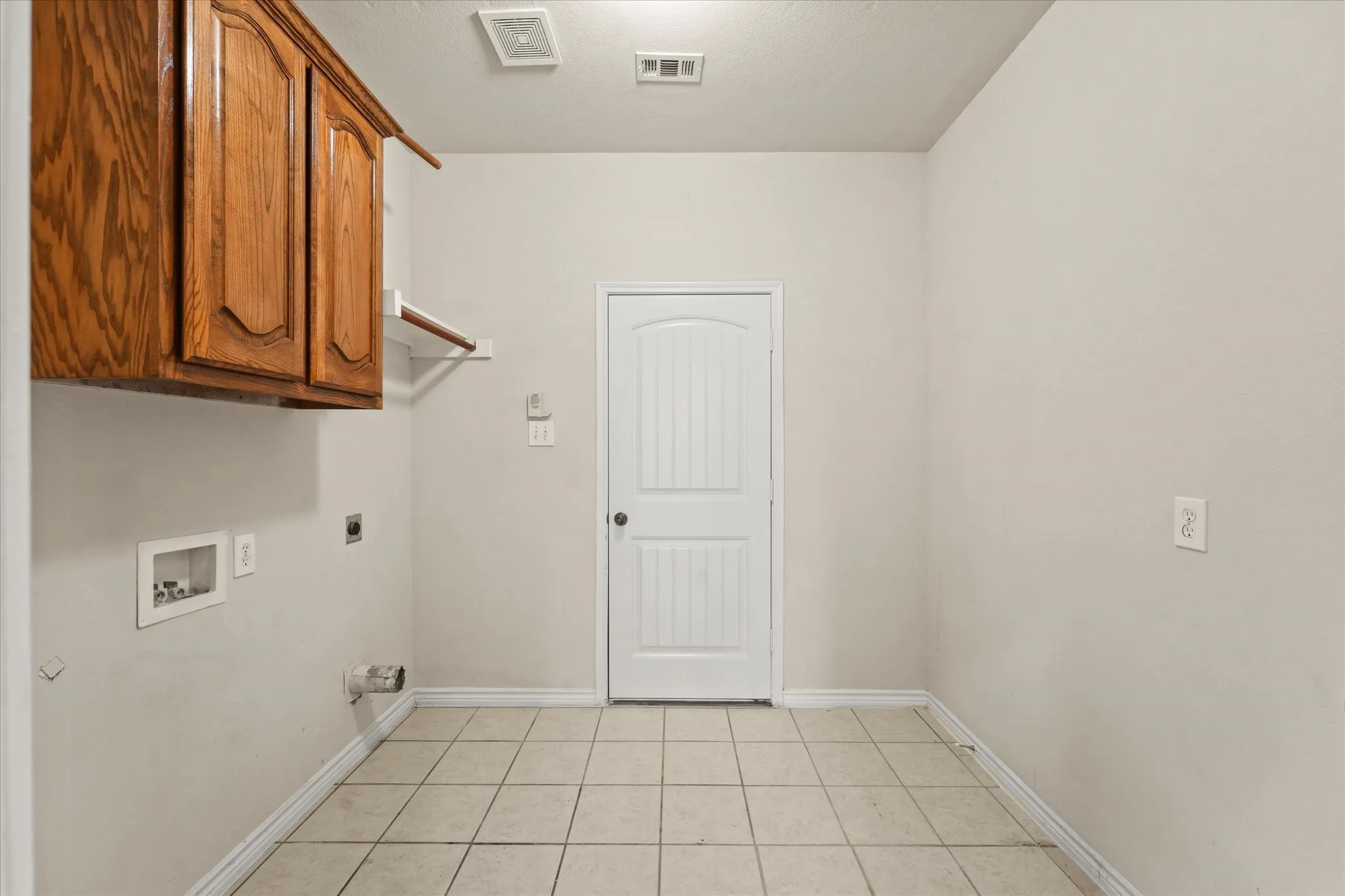 Washroom with cabinets, light tile flooring, electric dryer hookup, and hookup for a washing machine
