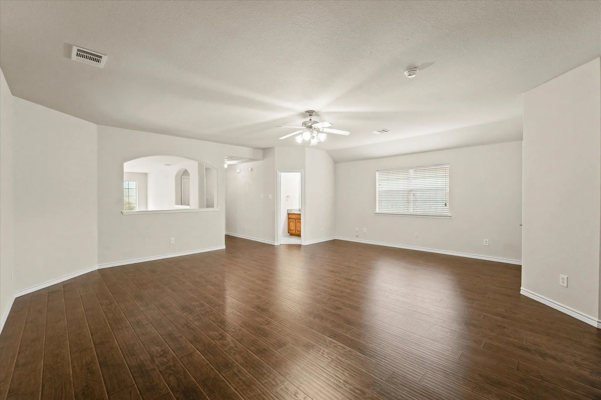 Empty room with dark wood-type flooring and ceiling fan