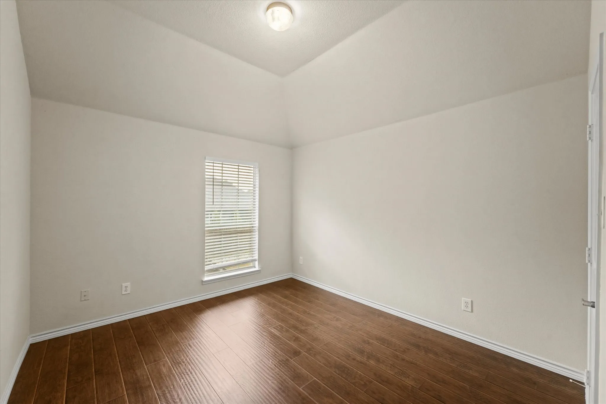 Empty room featuring lofted ceiling and wood-type flooring