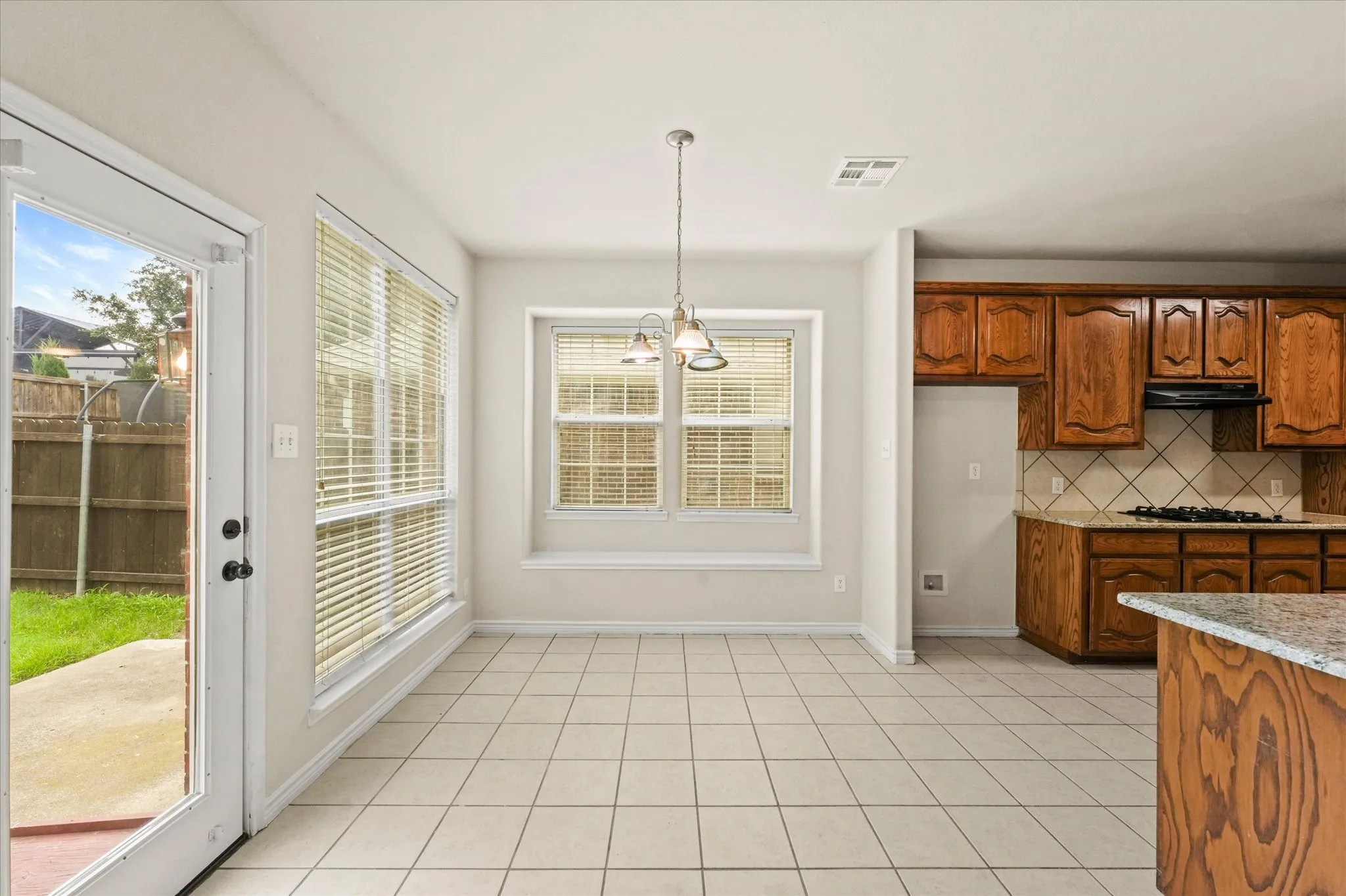 Kitchen with backsplash, hanging light fixtures, a wealth of natural light, and light tile flooring
